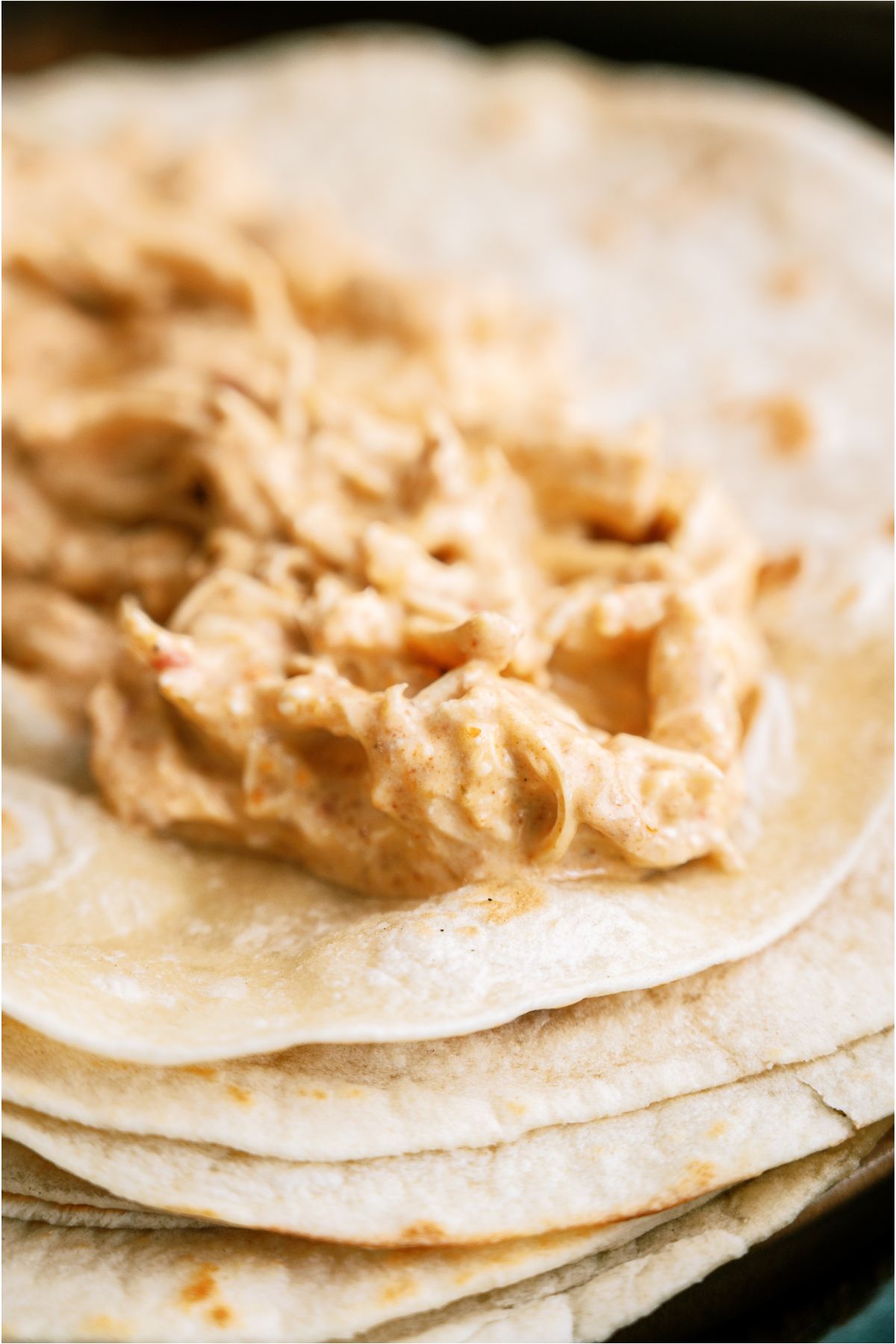 A scoop of cheesy chicken mixture in the center of a tortilla.