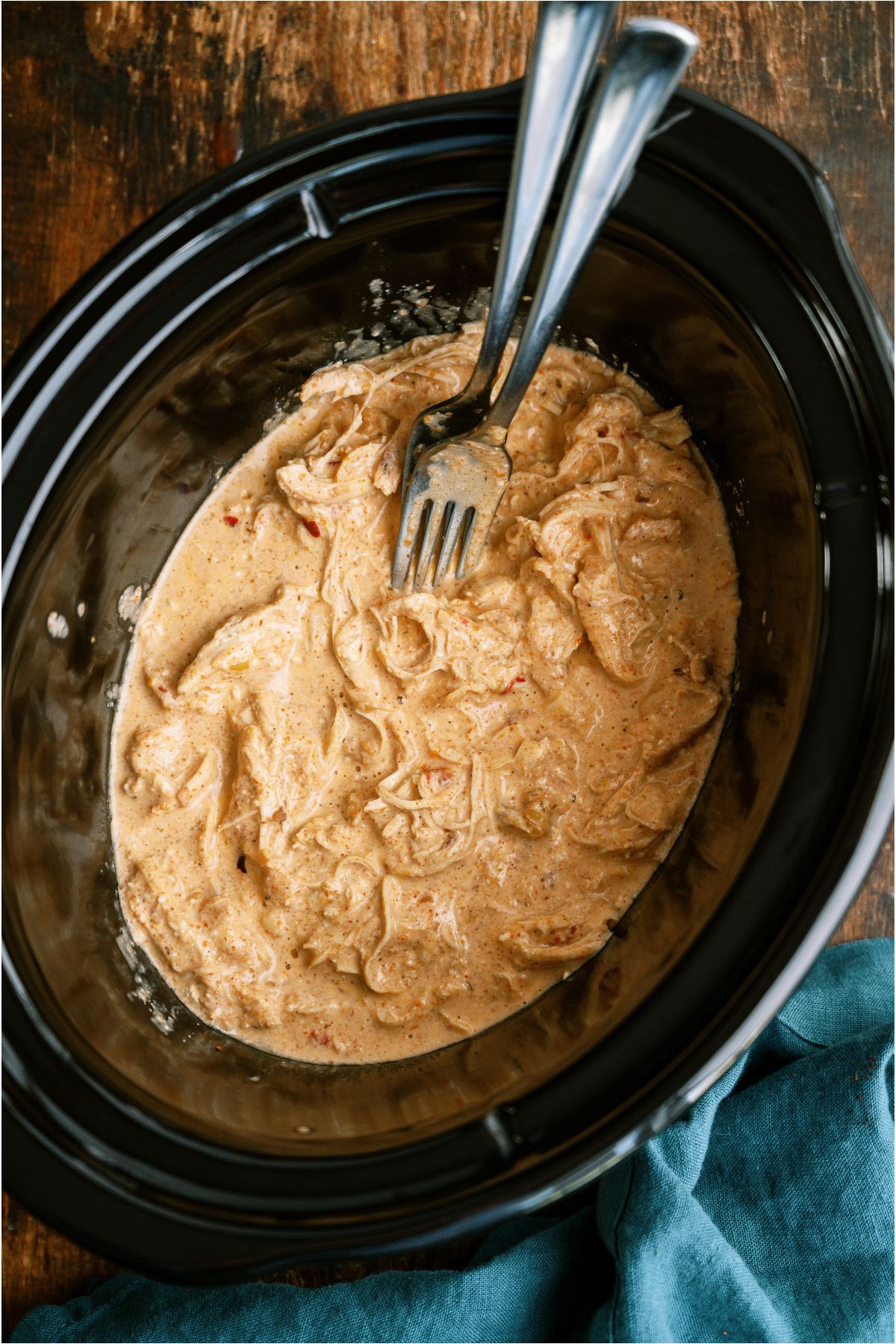 Shredded chicken mixture in the slow cooker with two forks.