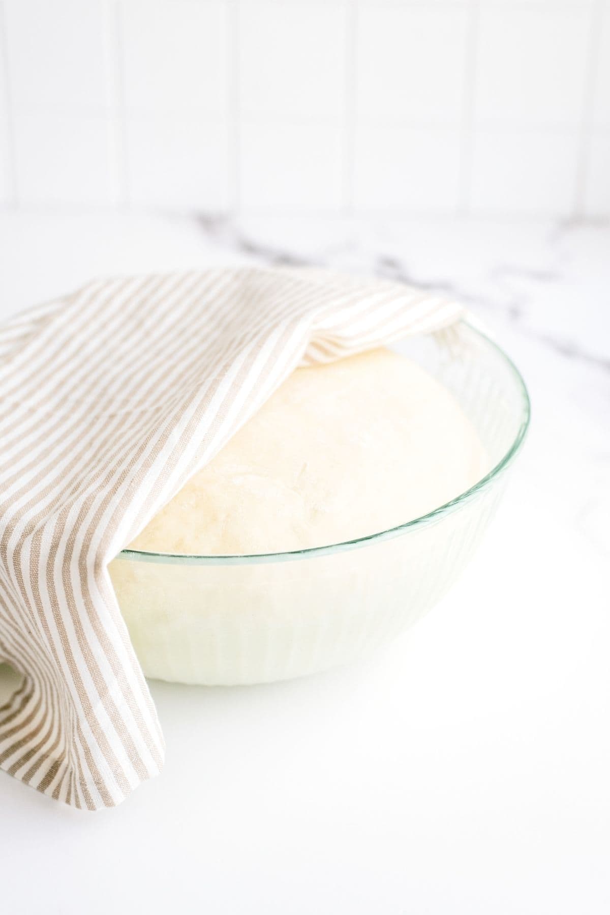 Roll dough in a mixing bowl with a towel on top