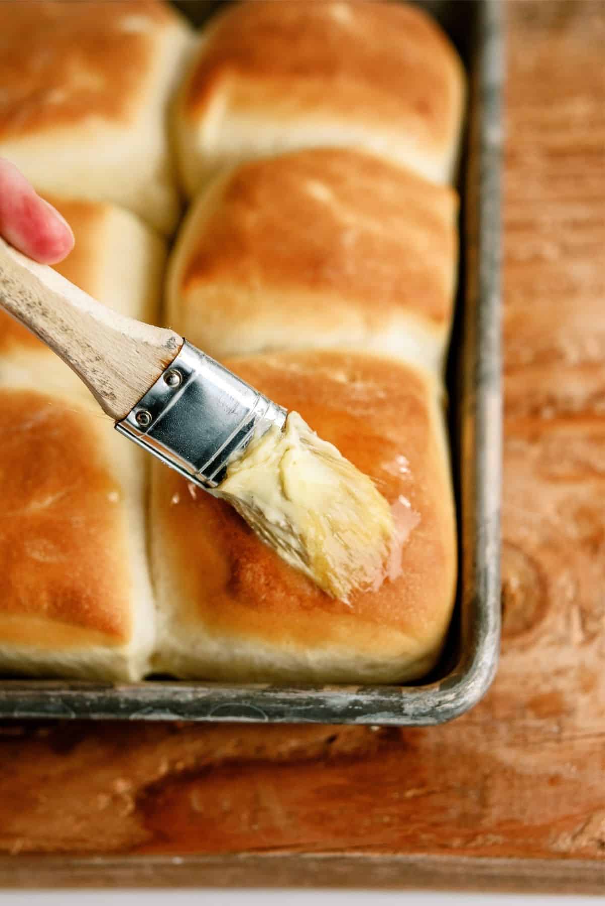 Brushing butter on freshly baked rolls