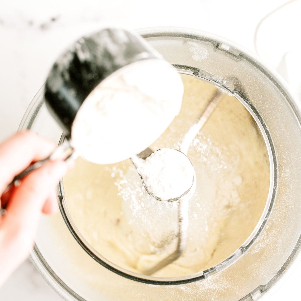 Adding one cup of flour slowly to the dough mixture