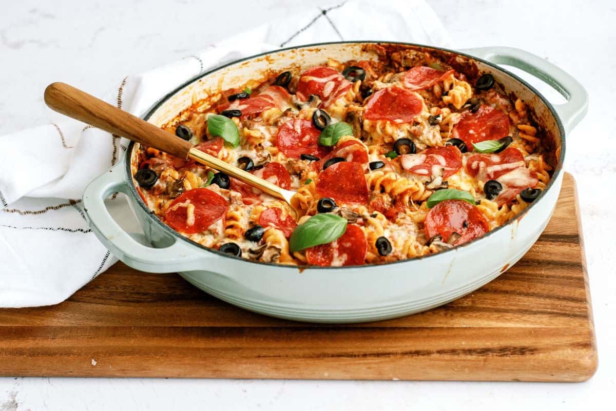 Cheesy Pizza Pasta Casserole in pan with a serving spoon