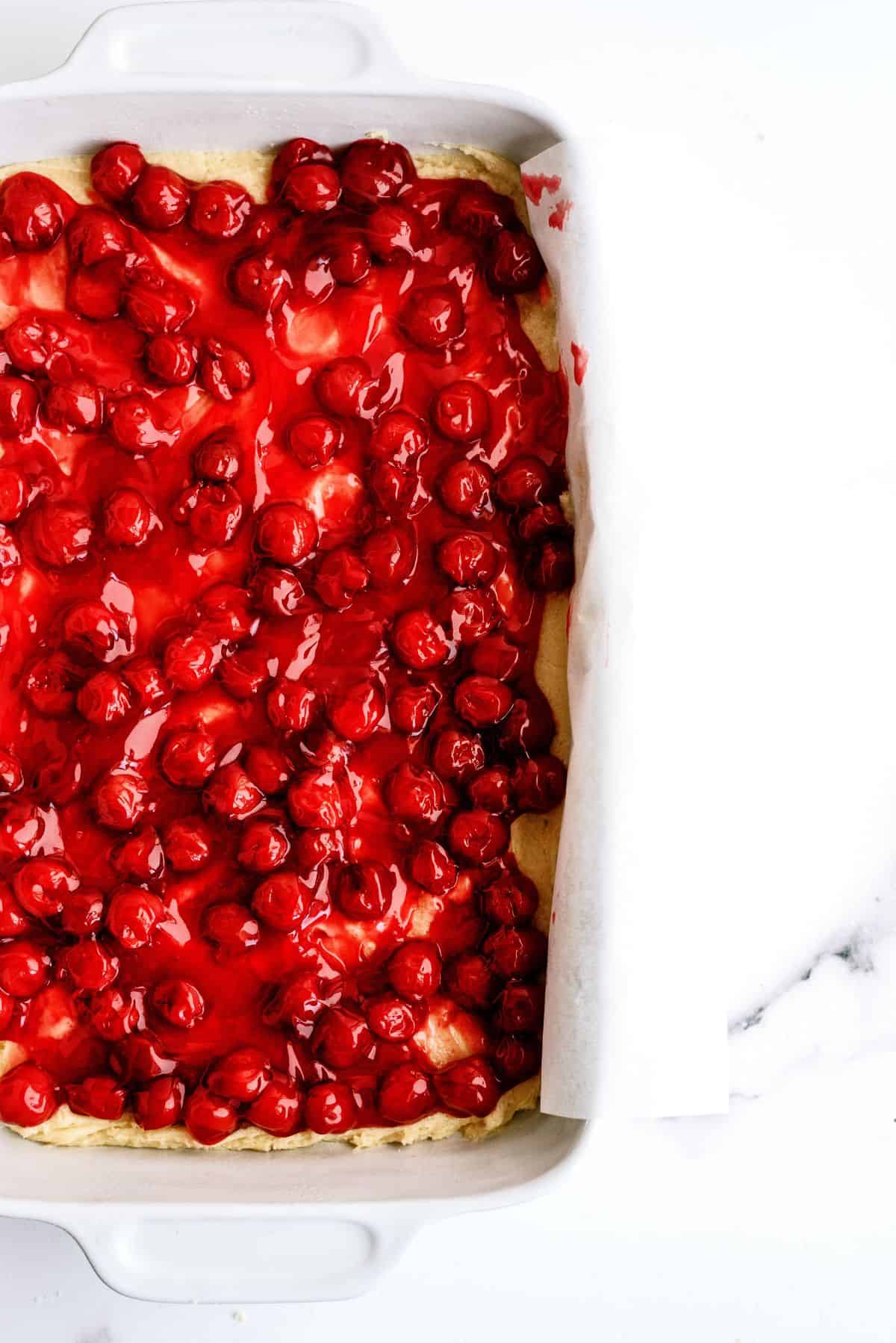 Cherry pie filling spread out over dough in pan