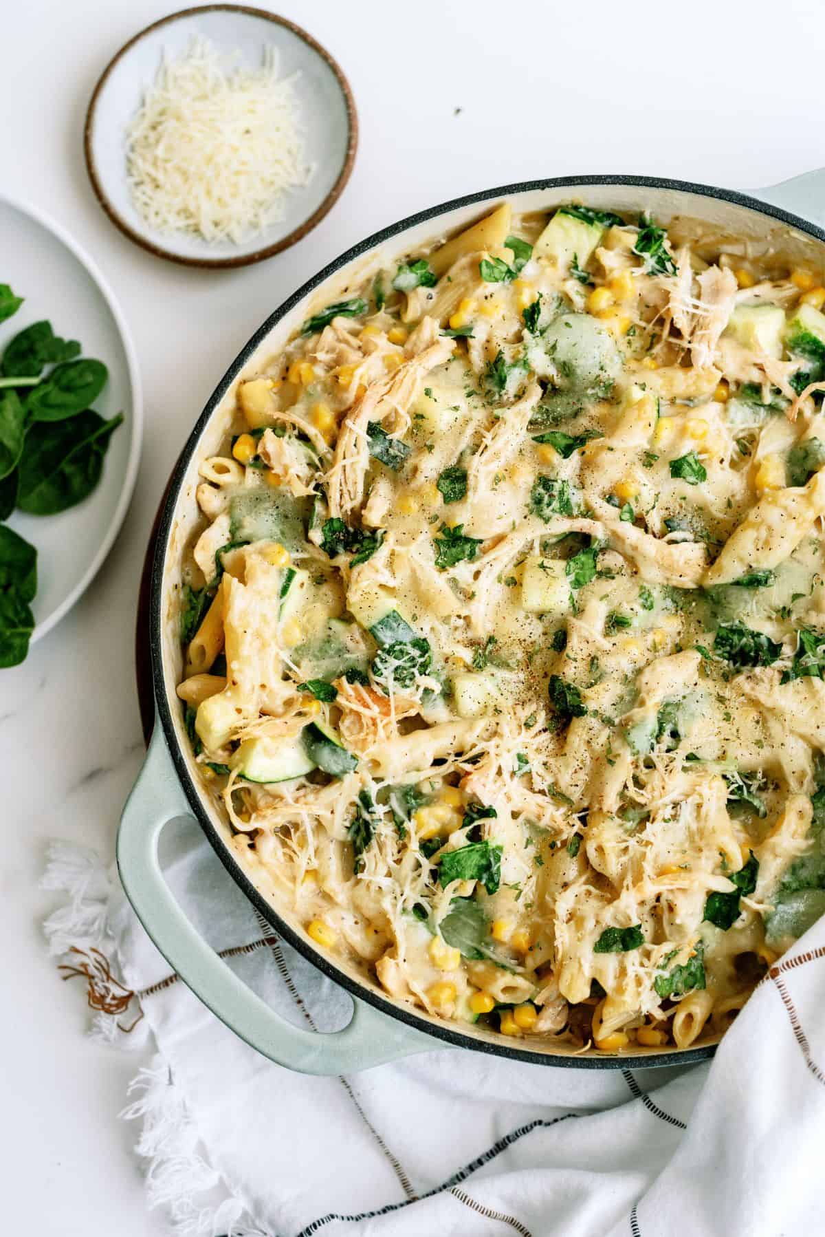 Chicken Pasta Casserole with Corn and Zucchini in a pan with a side of parmesan cheese