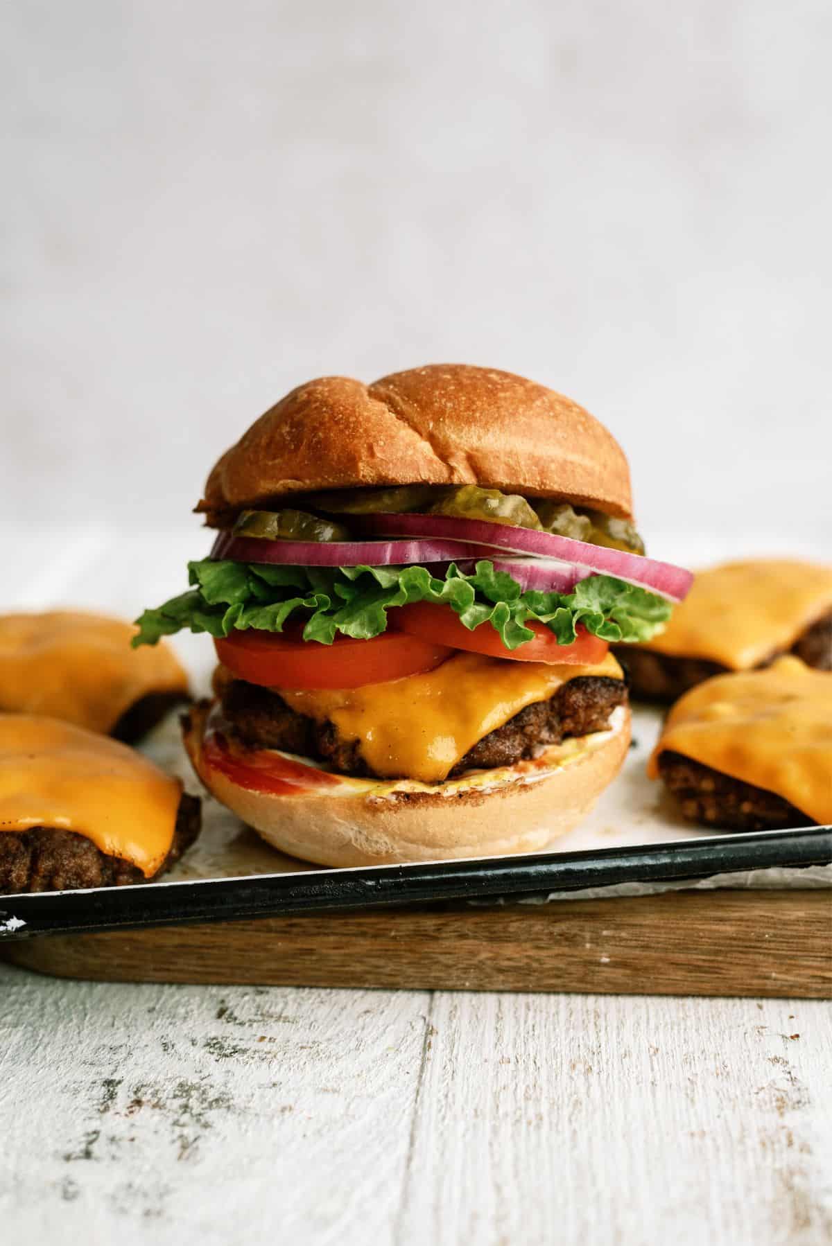 Classic Burger on a pan with other cheeseburger patties