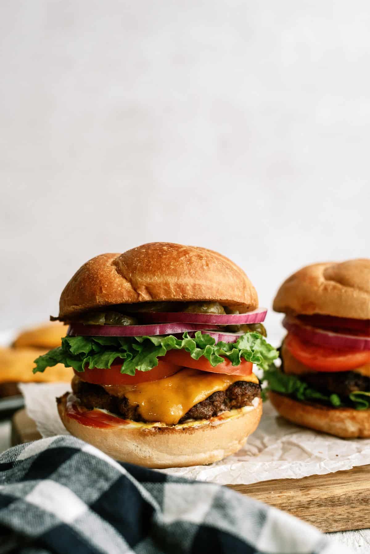 2 Classic Burgers with buns and toppings on a cutting board