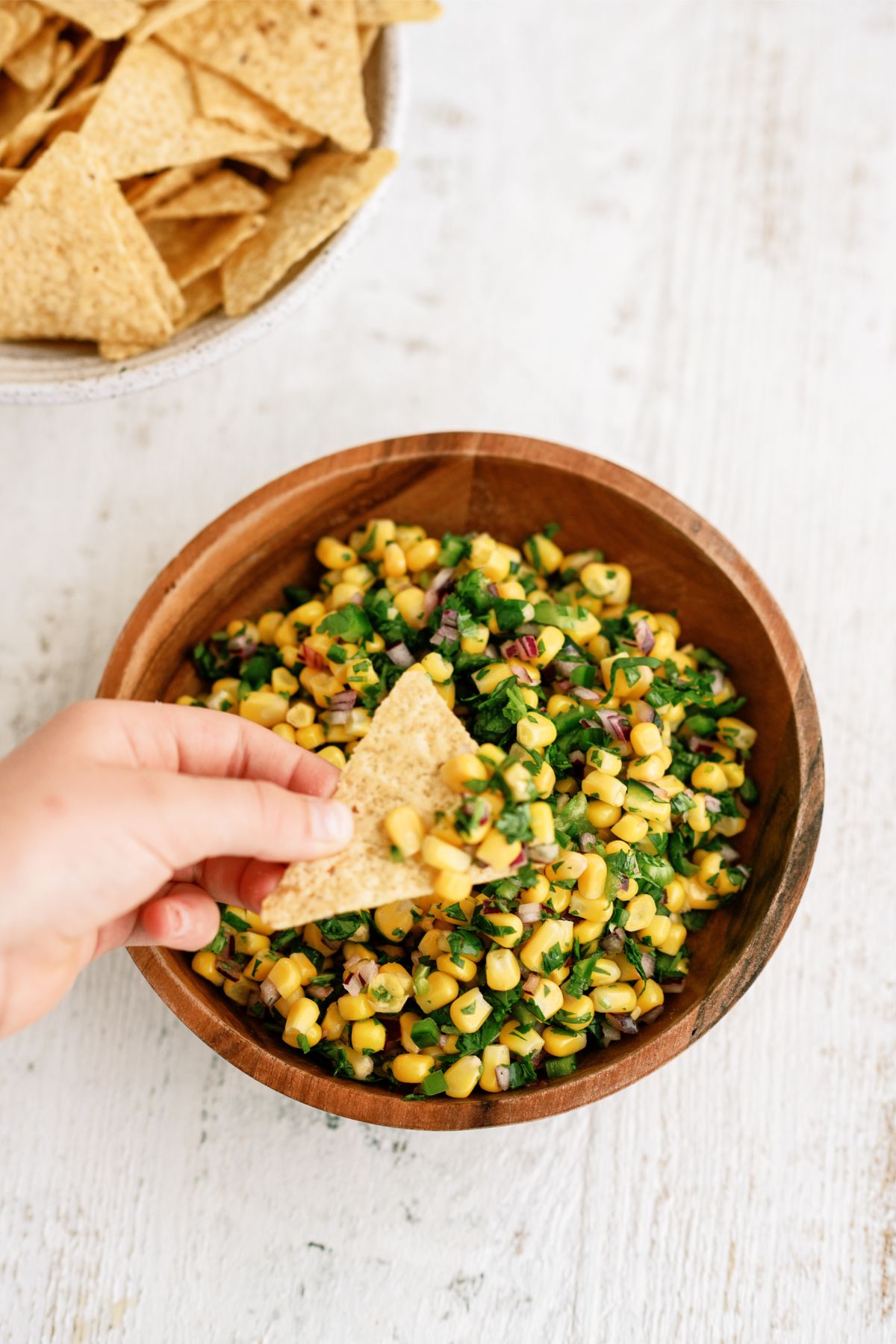 Dipping a chip in a bowl of Copycat Chipotle Corn Salsa