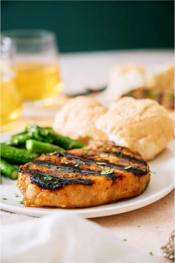 Grilled Pork Medallion on a plate with asparagus and biscuits.