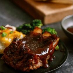 A plate of ribs with gravy and broccoli