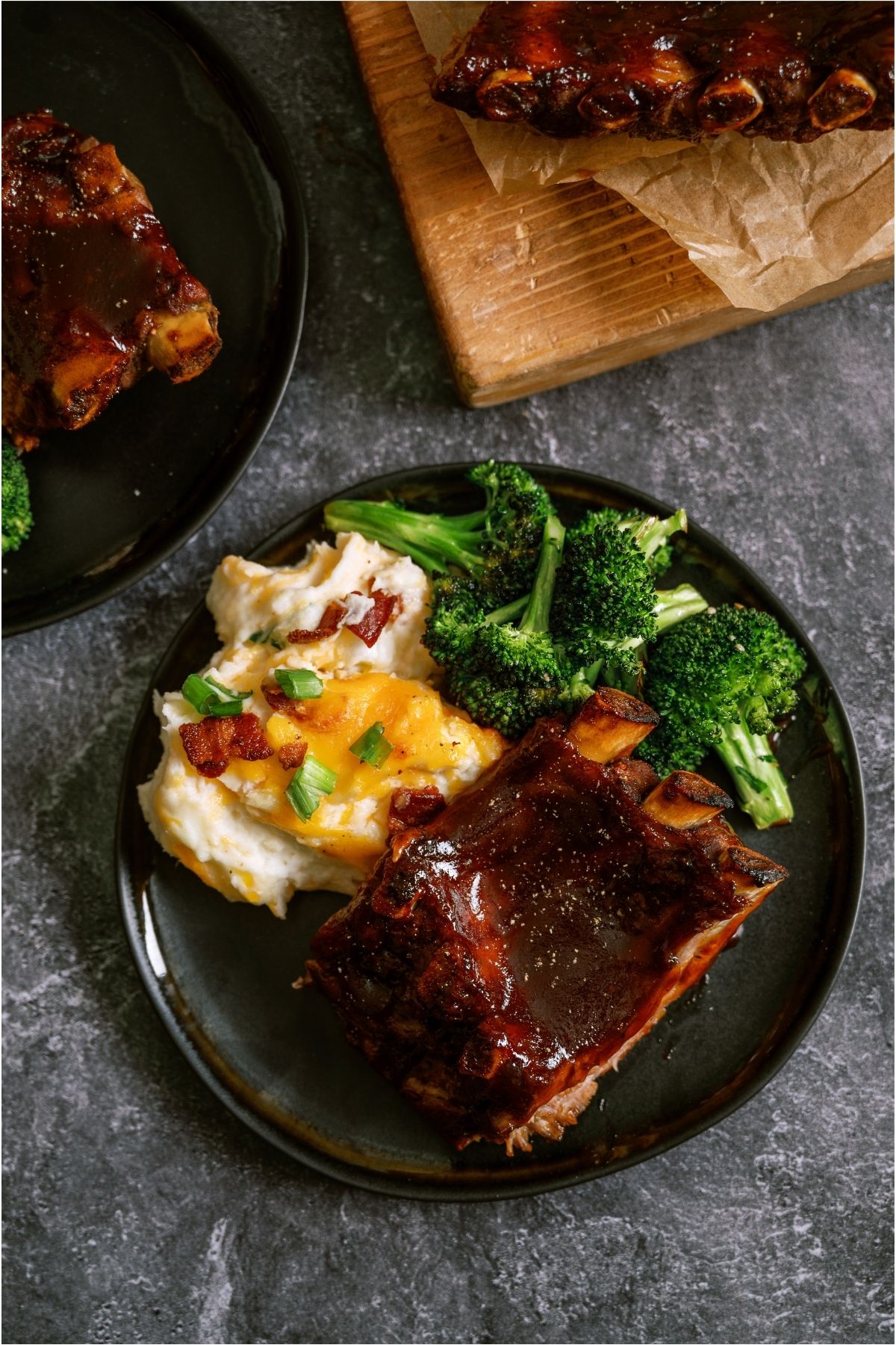 Top view of Instant Pot Bone-In Ribs on a plate with a side of potatoes and broccoli.