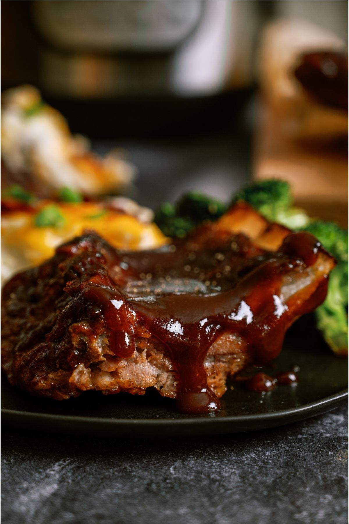Close up view of Instant Pot Bone-In Ribs on a plate with a side of potatoes and broccoli.