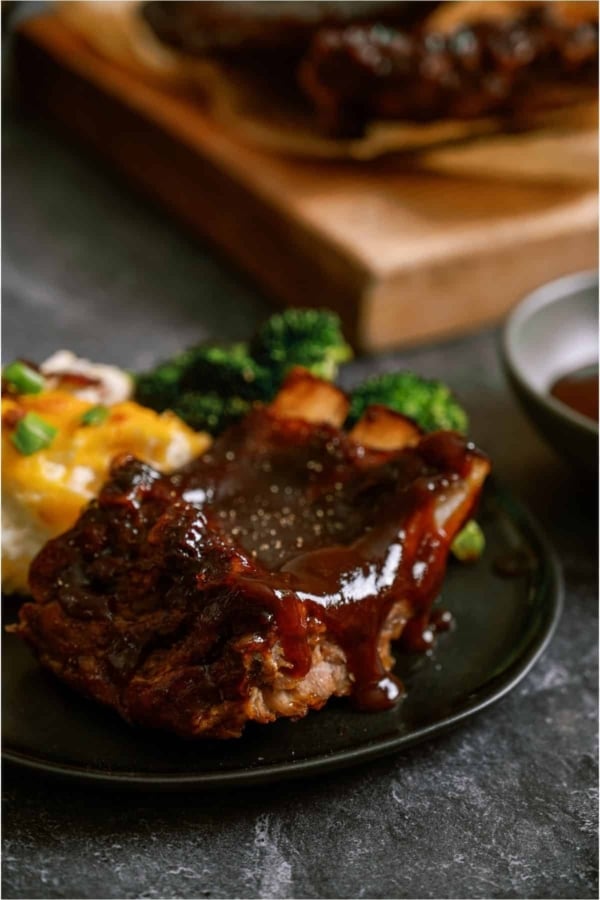 A plate of ribs with gravy and broccoli