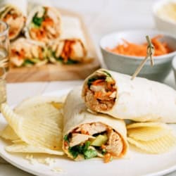An Instant Pot Buffalo Chicken Wrap cut in half on a plate with potato chips.