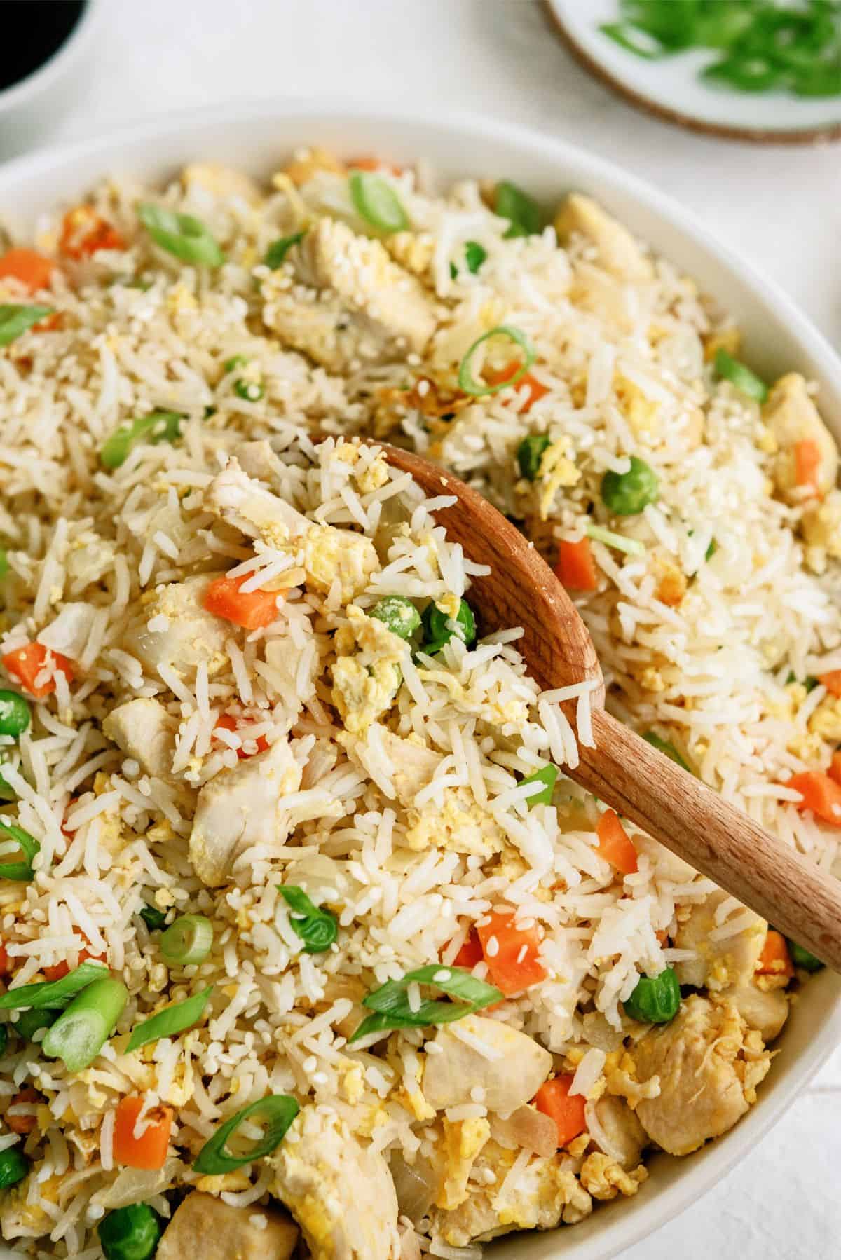 Close up of Instant Pot Chicken Fried Rice in a bowl with a wooden spoon