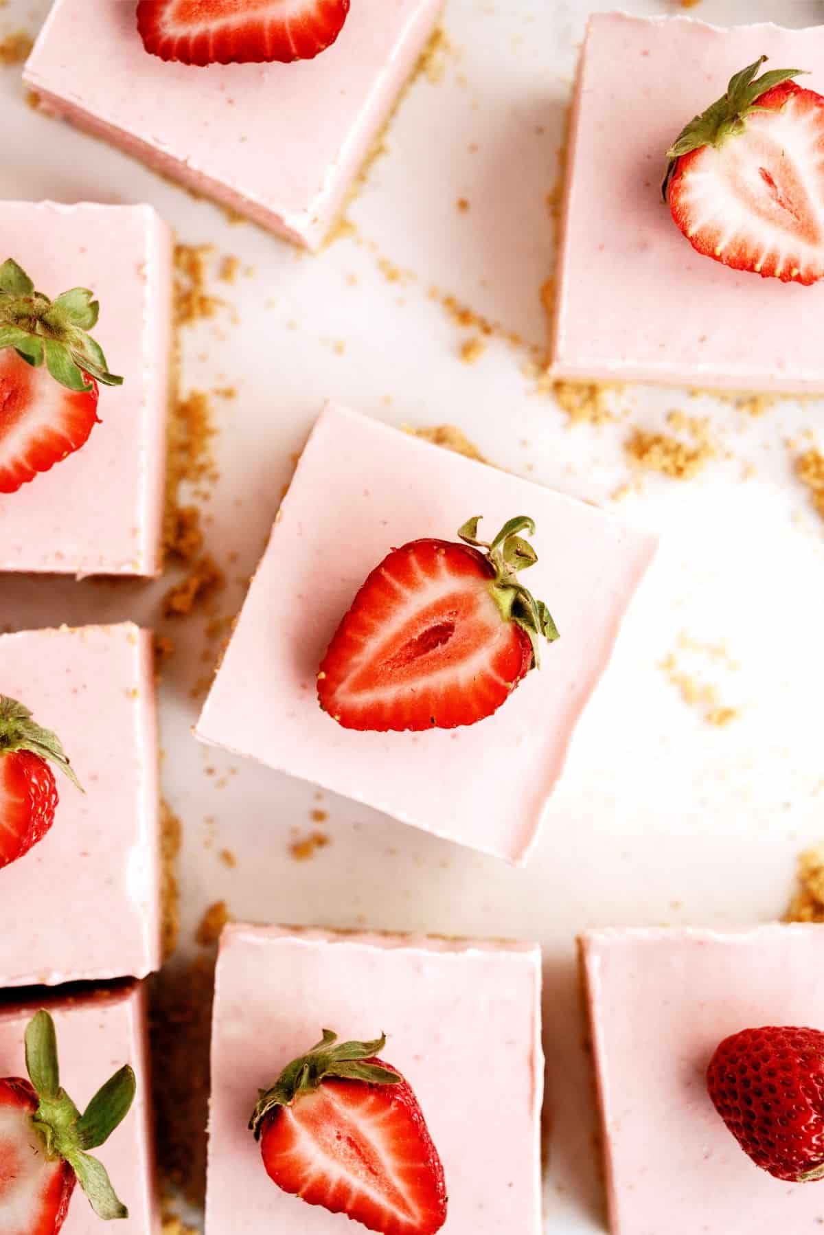 No Bake Strawberry Cheesecake Bars cut into squares and topped with fresh strawberries