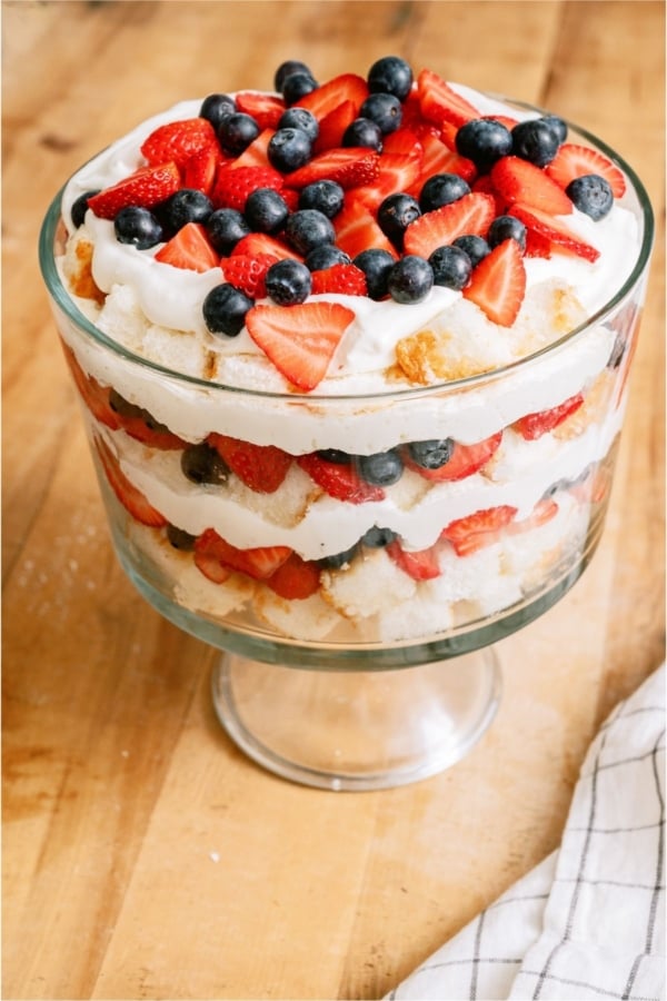Patriotic Berry Trifle in trifle dish on a wooden countertop.