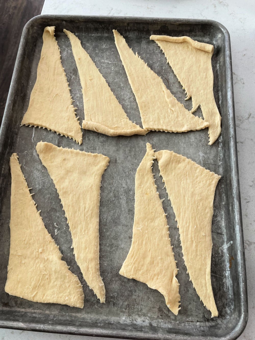 Crescent rolls separated into 8 equal pieces on sheet pan