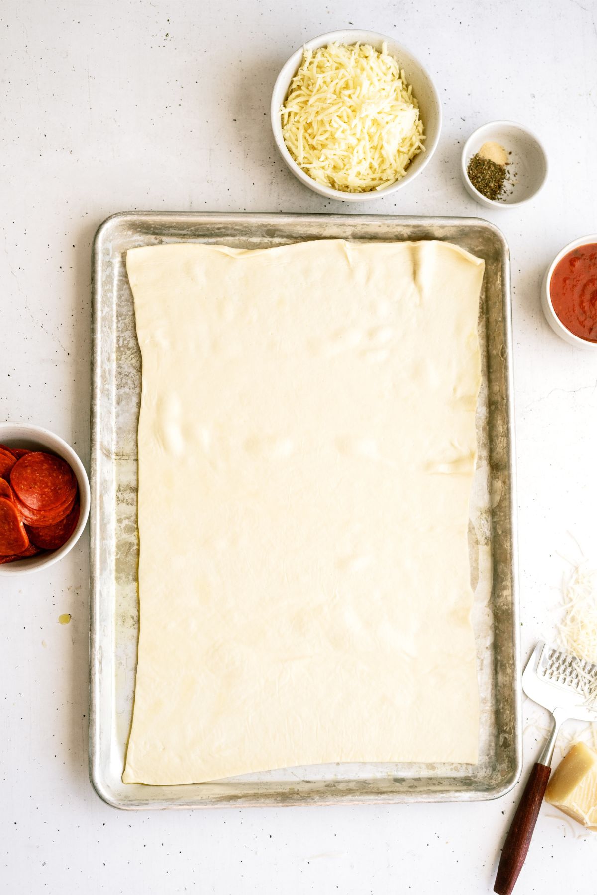 Pizza dough spread out on baking sheet