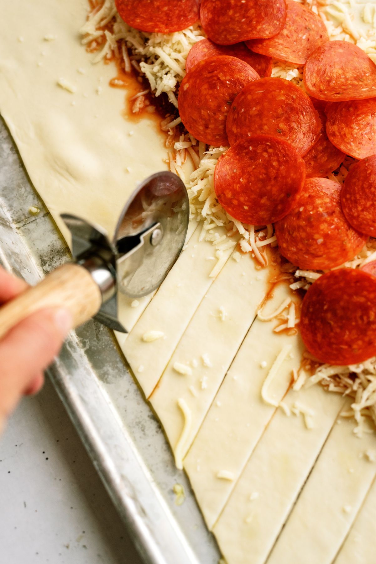 Pizza cutter slicing the pizza dough