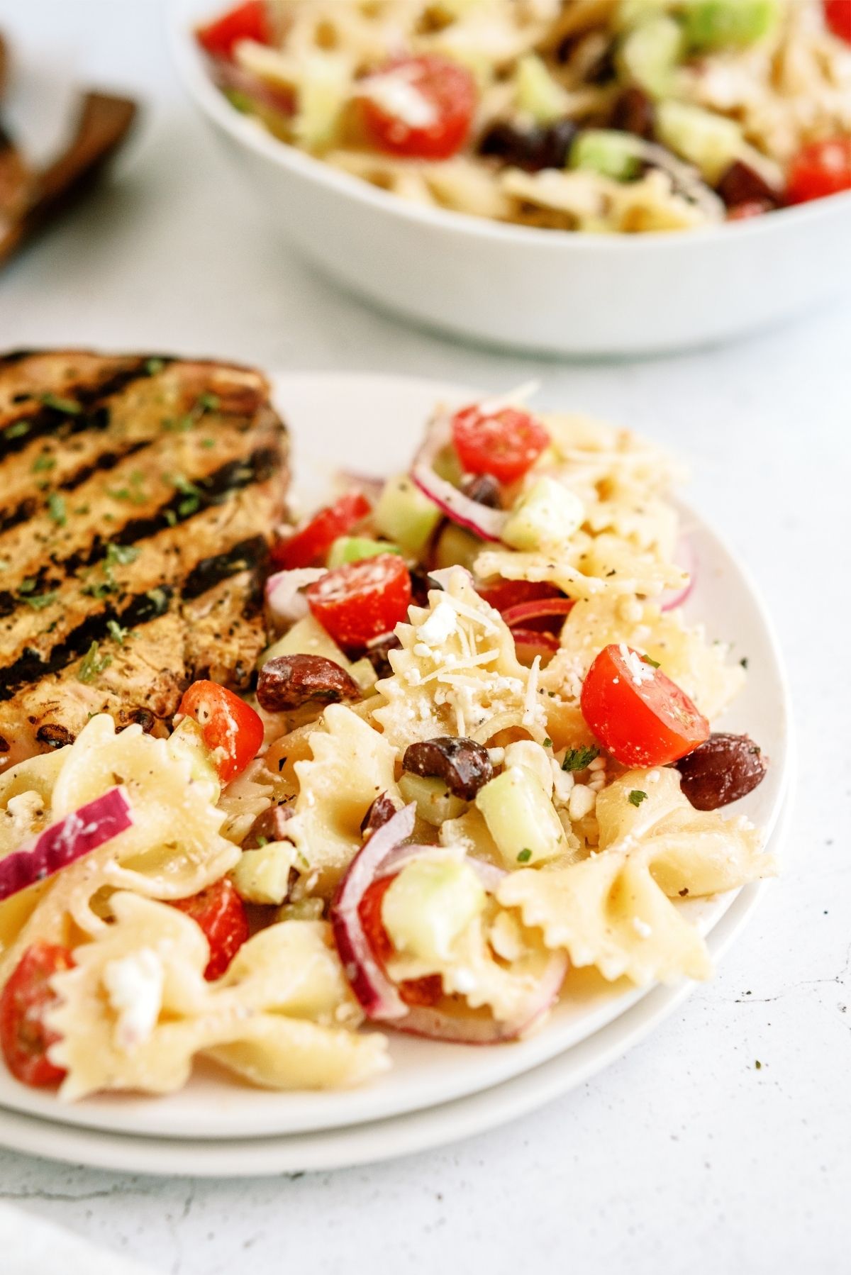 A serving of Greek Pasta Salad on a plate with grilled chicken