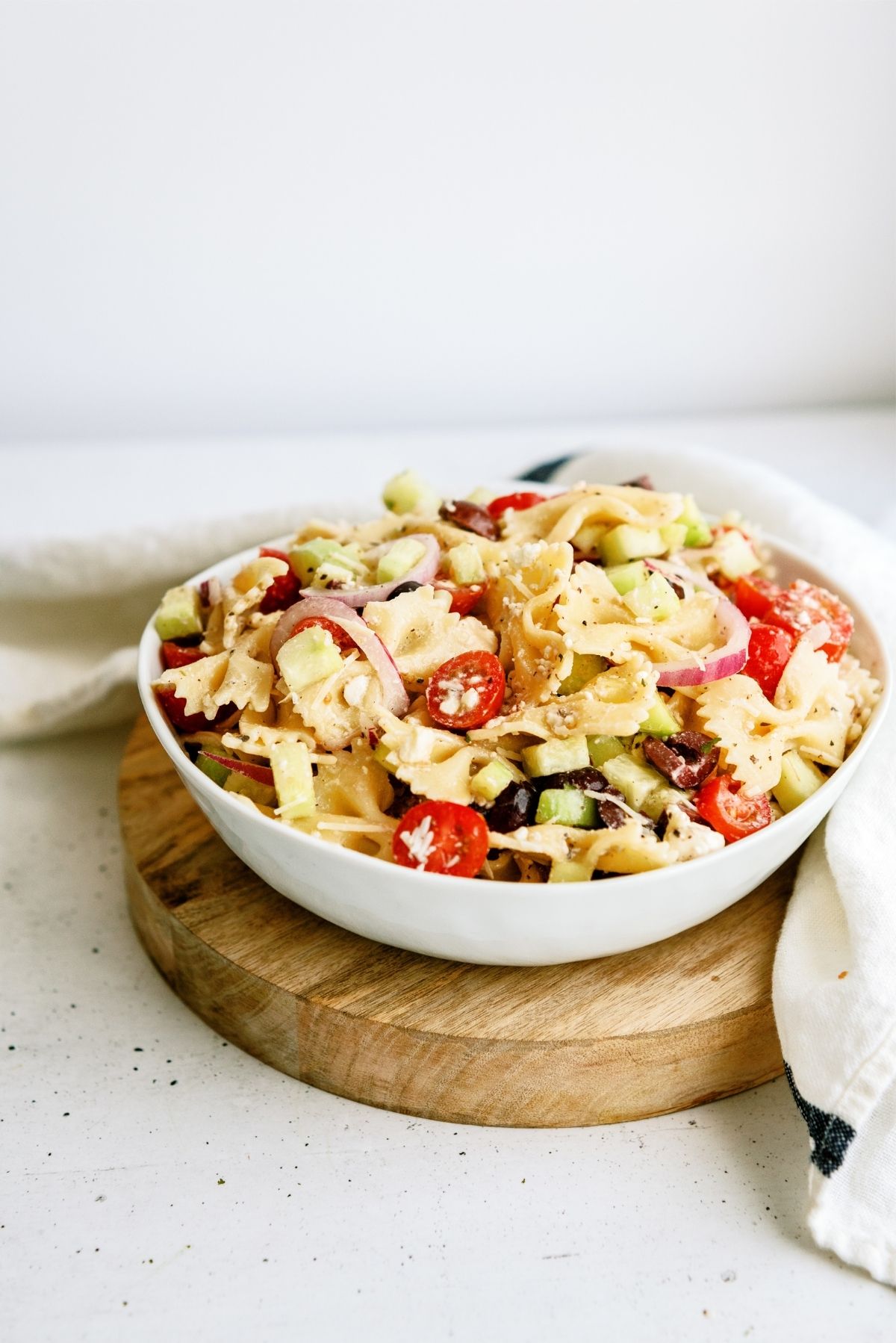 Greek Pasta Salad in a bowl on a wooden riser