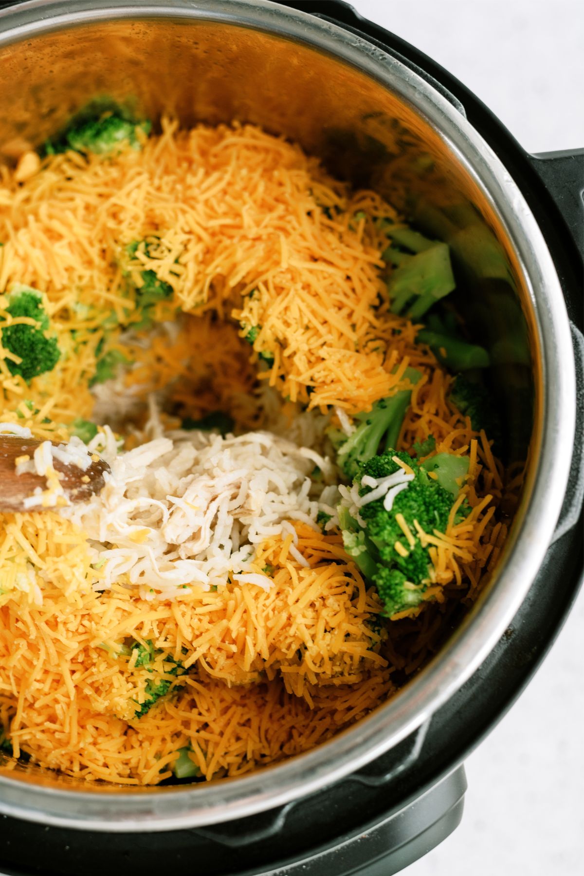 Shredded cheese on top of chicken, rice and broccoli in the Instant Pot