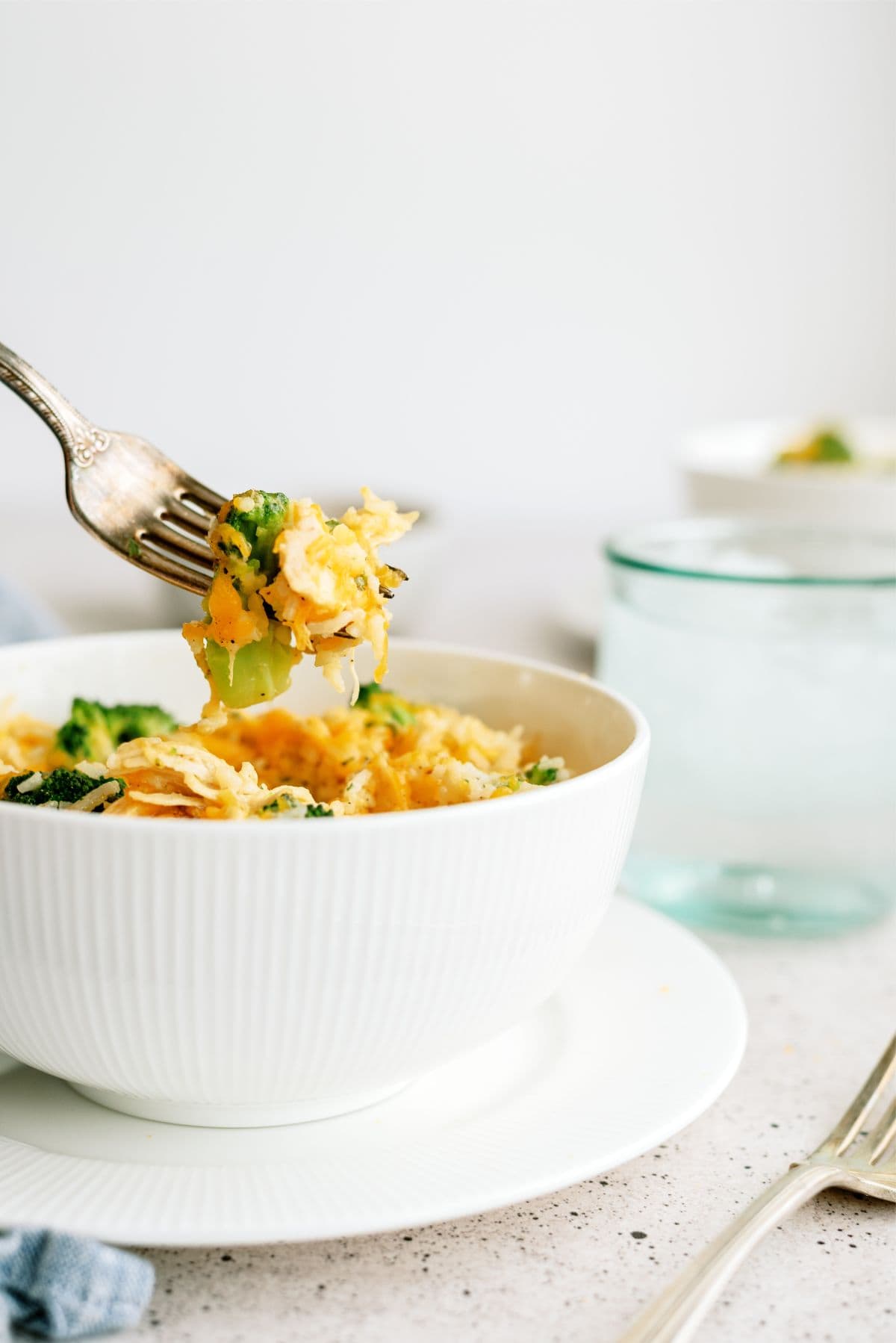 Fork lifting a bite of Instant Pot Cheesy Broccoli Chicken and Rice out of a bowl