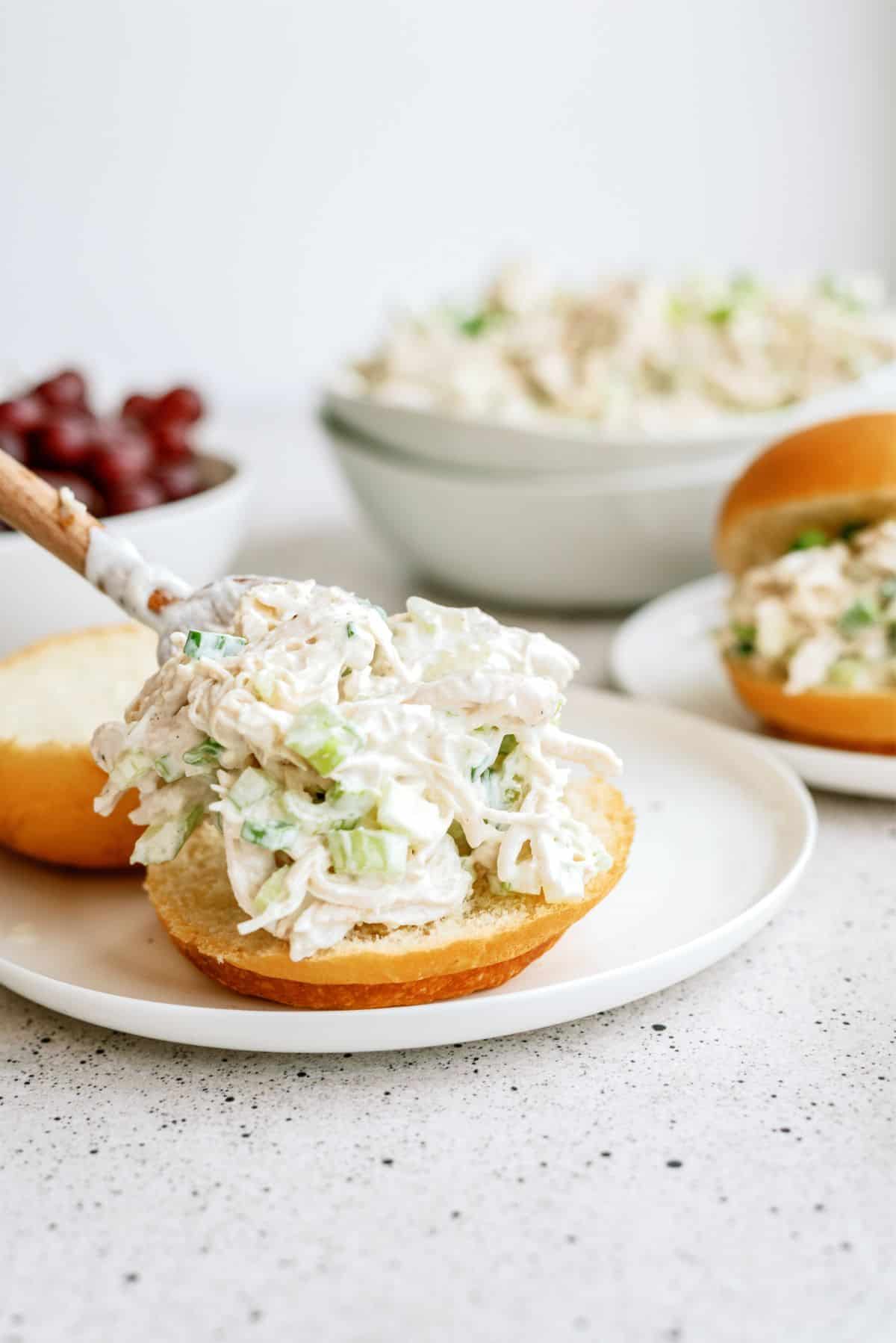 Scooping Kneaders Copycat Chicken Salad onto a bun