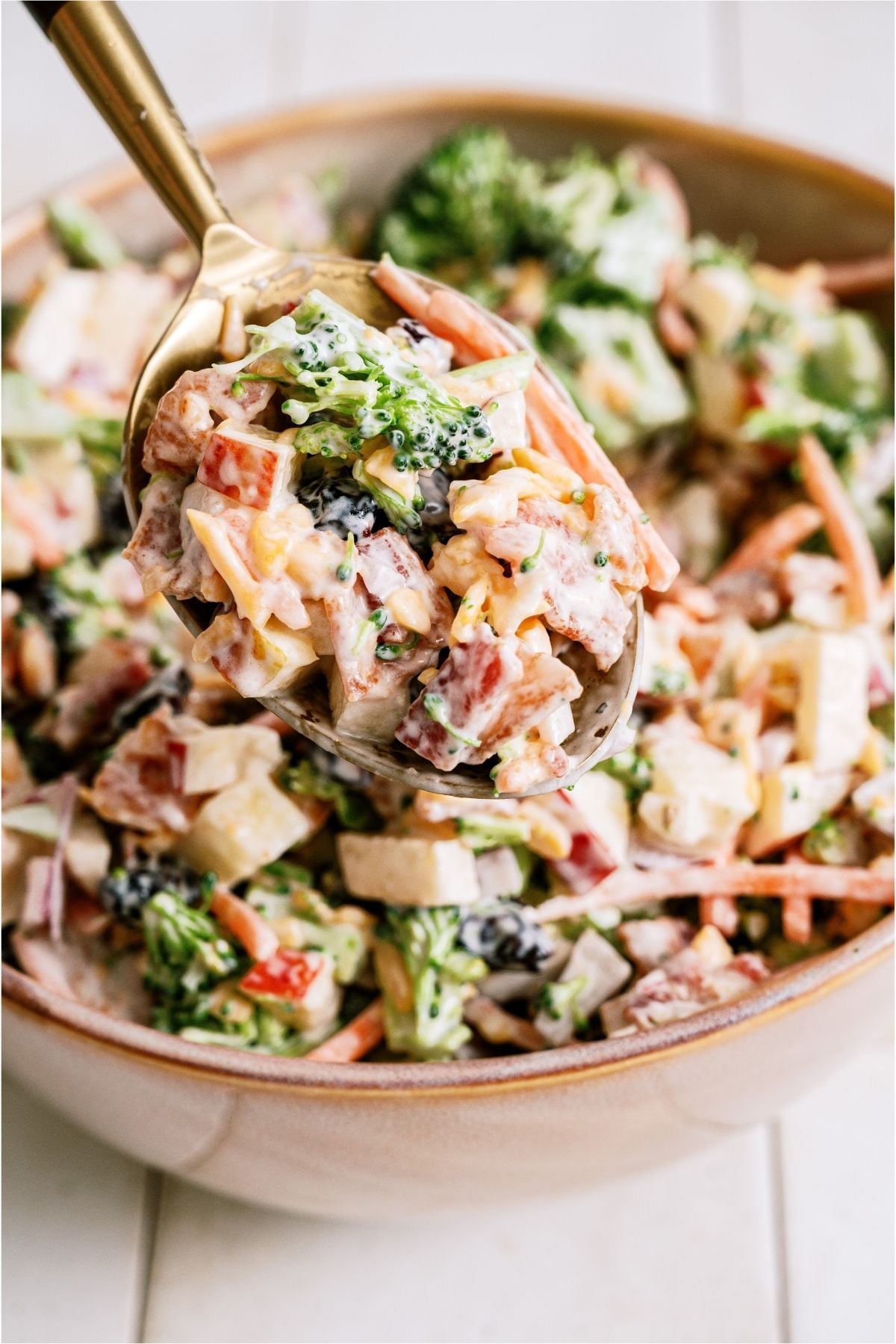 A spoon lifting up a bite of Loaded Broccoli Salad out of a bowl.