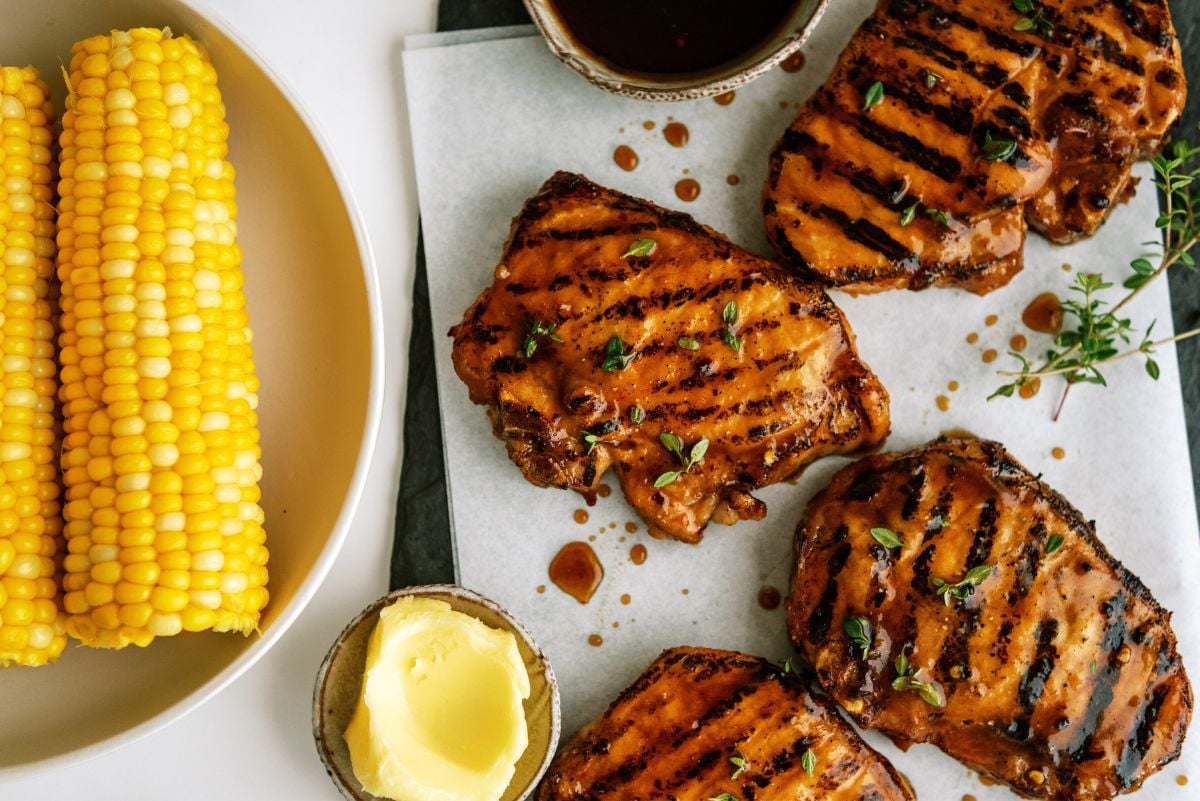 Perfectly Juicy Grilled Pork Chops on a baking sheet with a bowl of corn on the cob