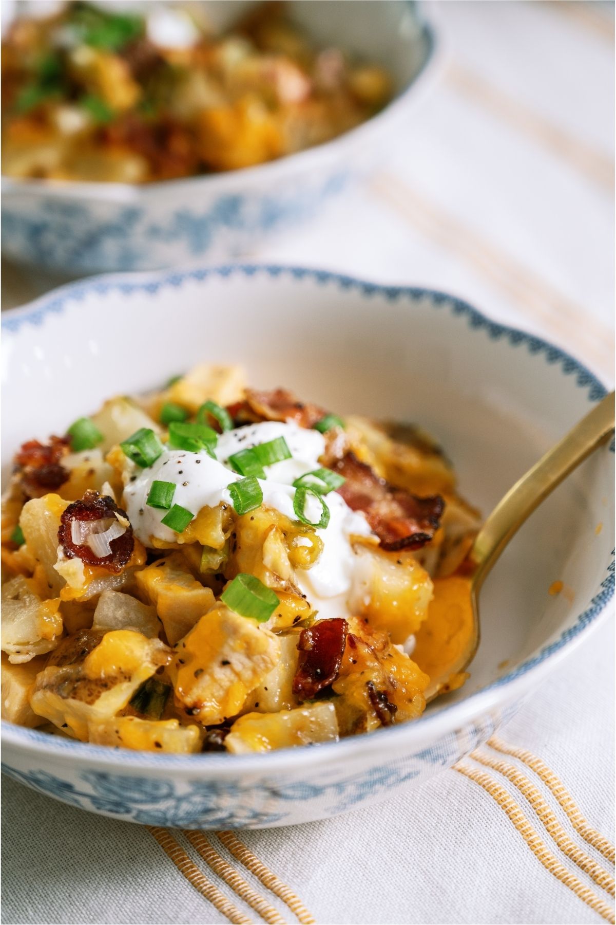 A white bowl of Slow Cooker Loaded Chicken and Potato Casserole with a spoon.