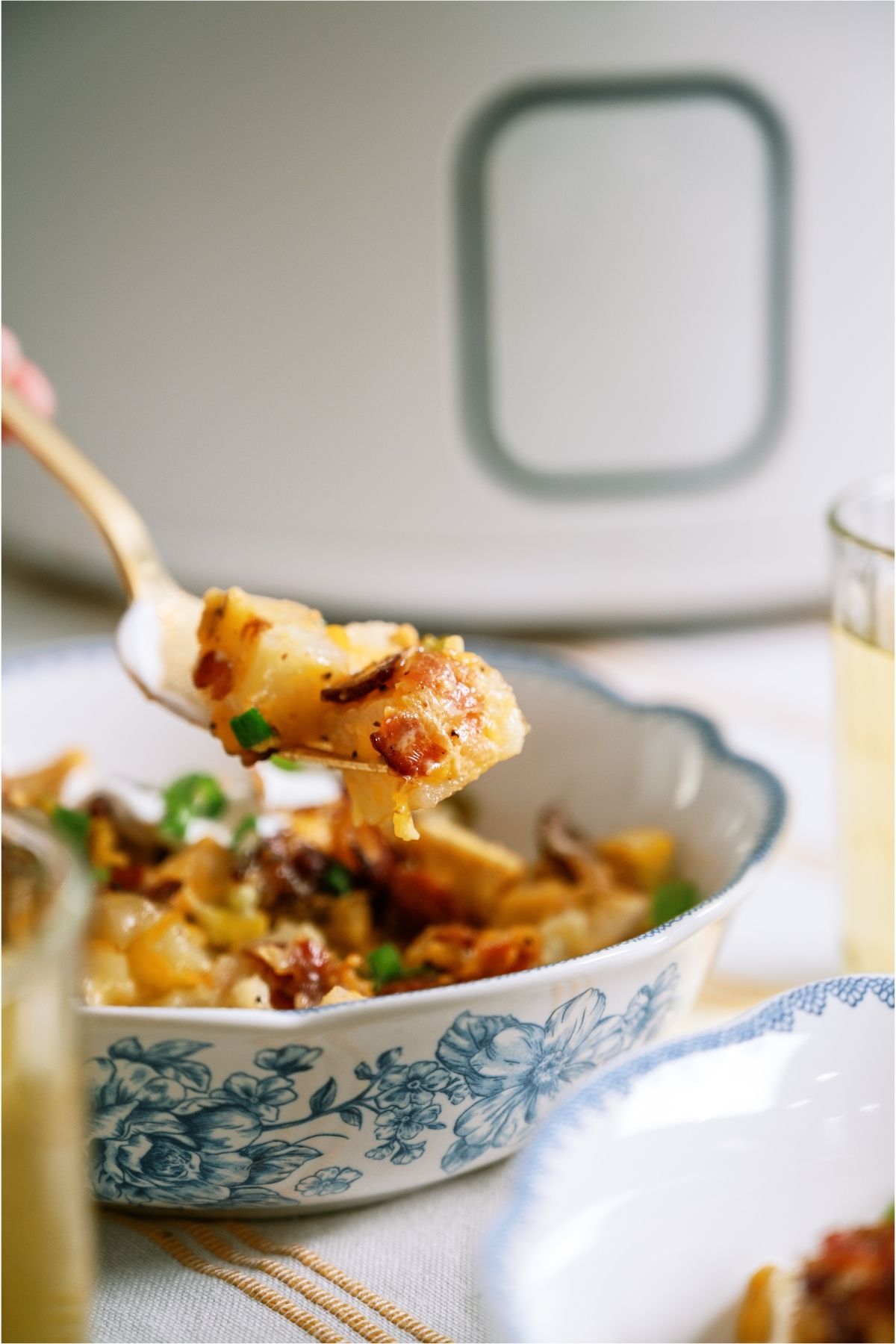A spoon lifting out a bite of Slow Cooker Loaded Chicken and Potato Casserole out of a bowl.