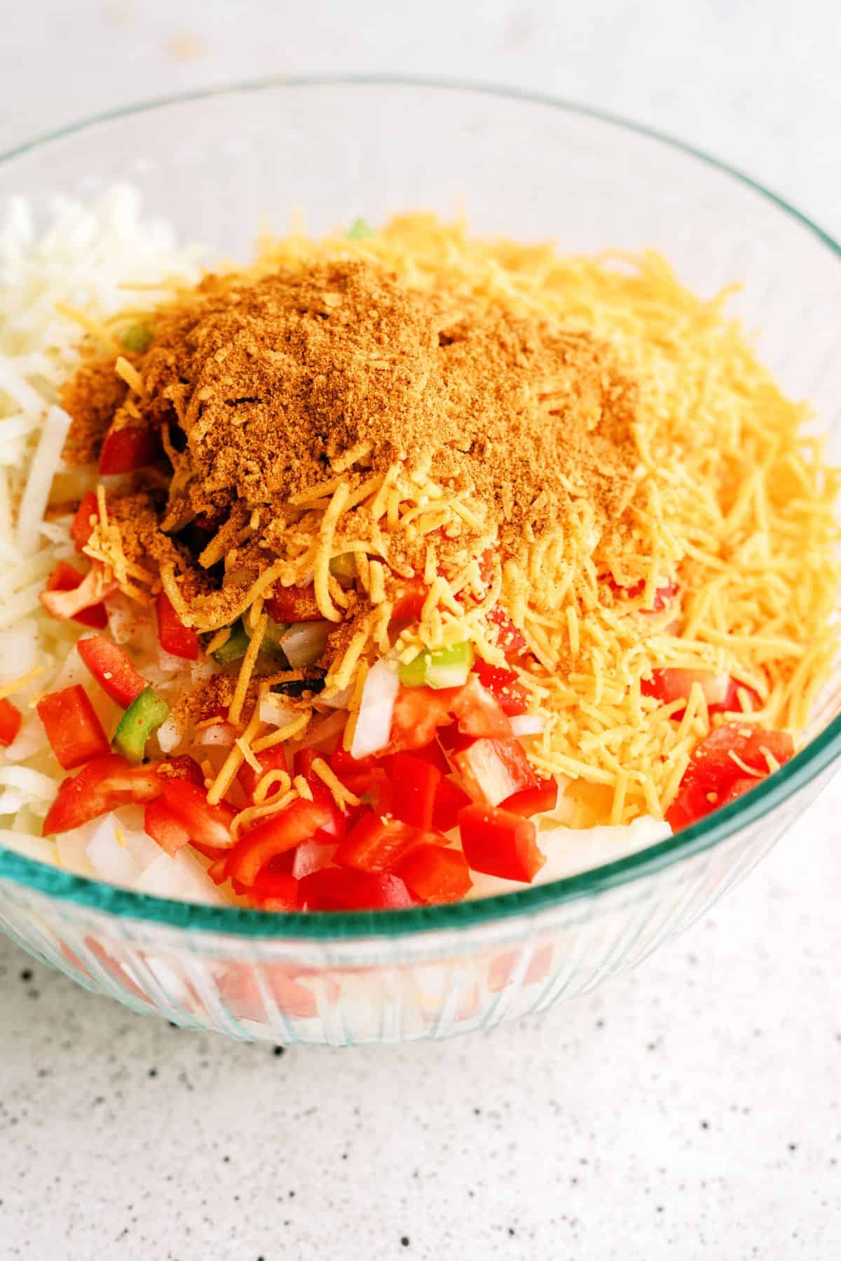 Taco seasoning added on top of diced veggies in a bowl