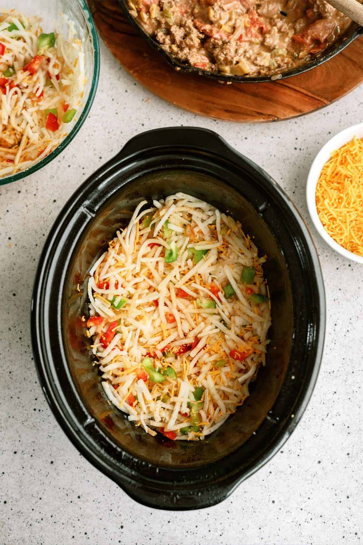 Half the hashbrown mixture added to the bottom of the slow cooker