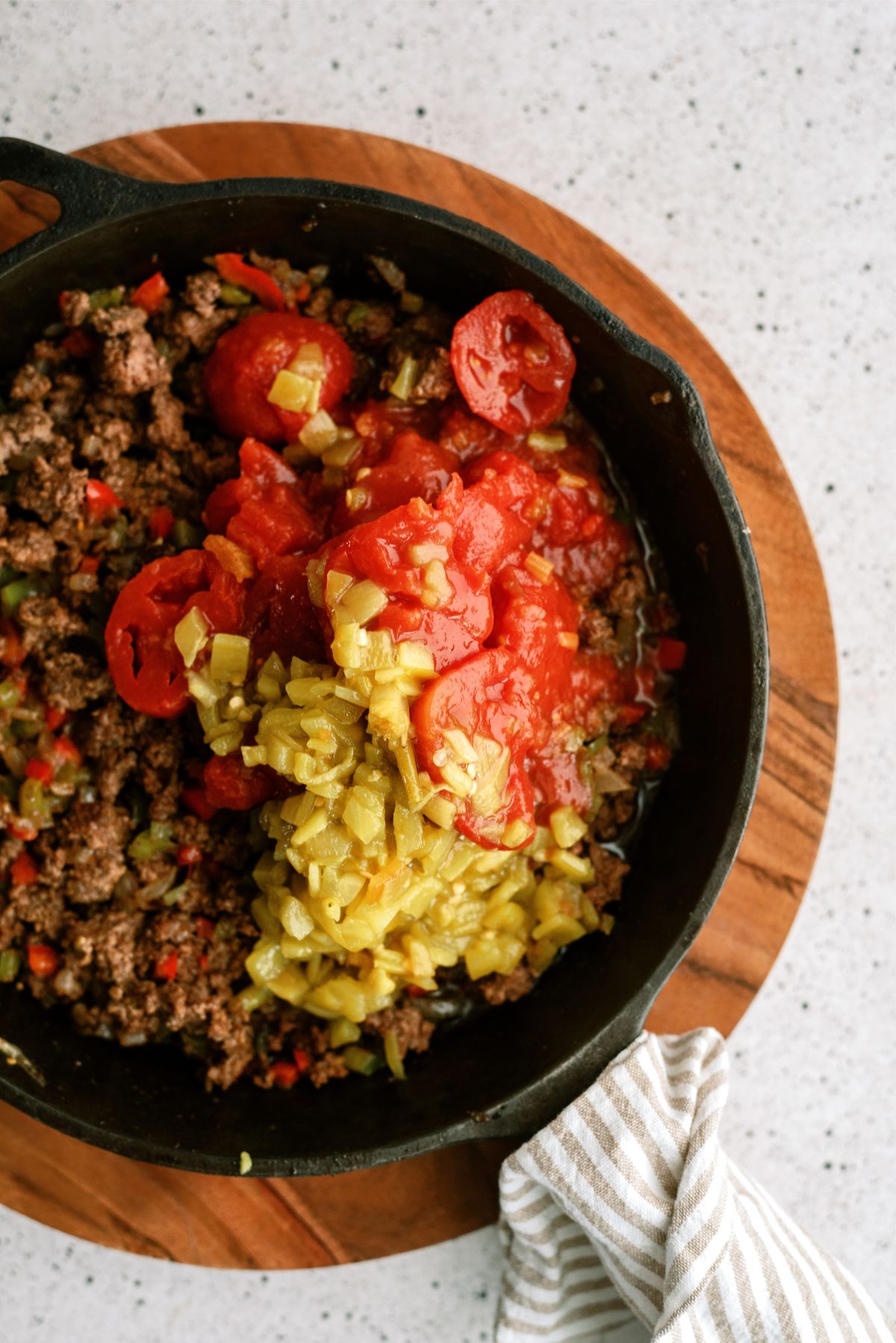 ground beef in pan with green chilies and stewed tomatoes