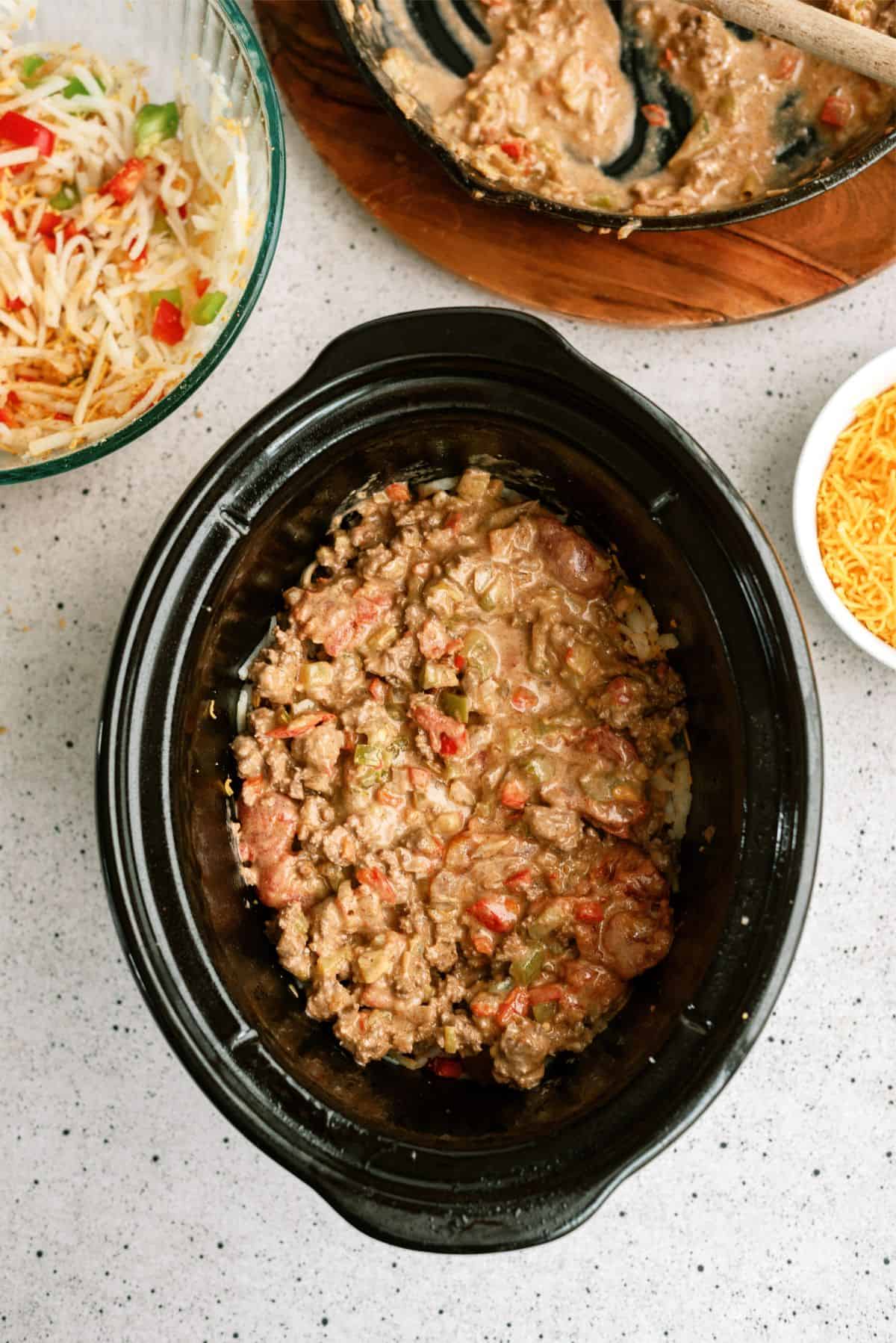 1/2 the hamburger mixture layered on top of the hashbrown mixture in slow cooker