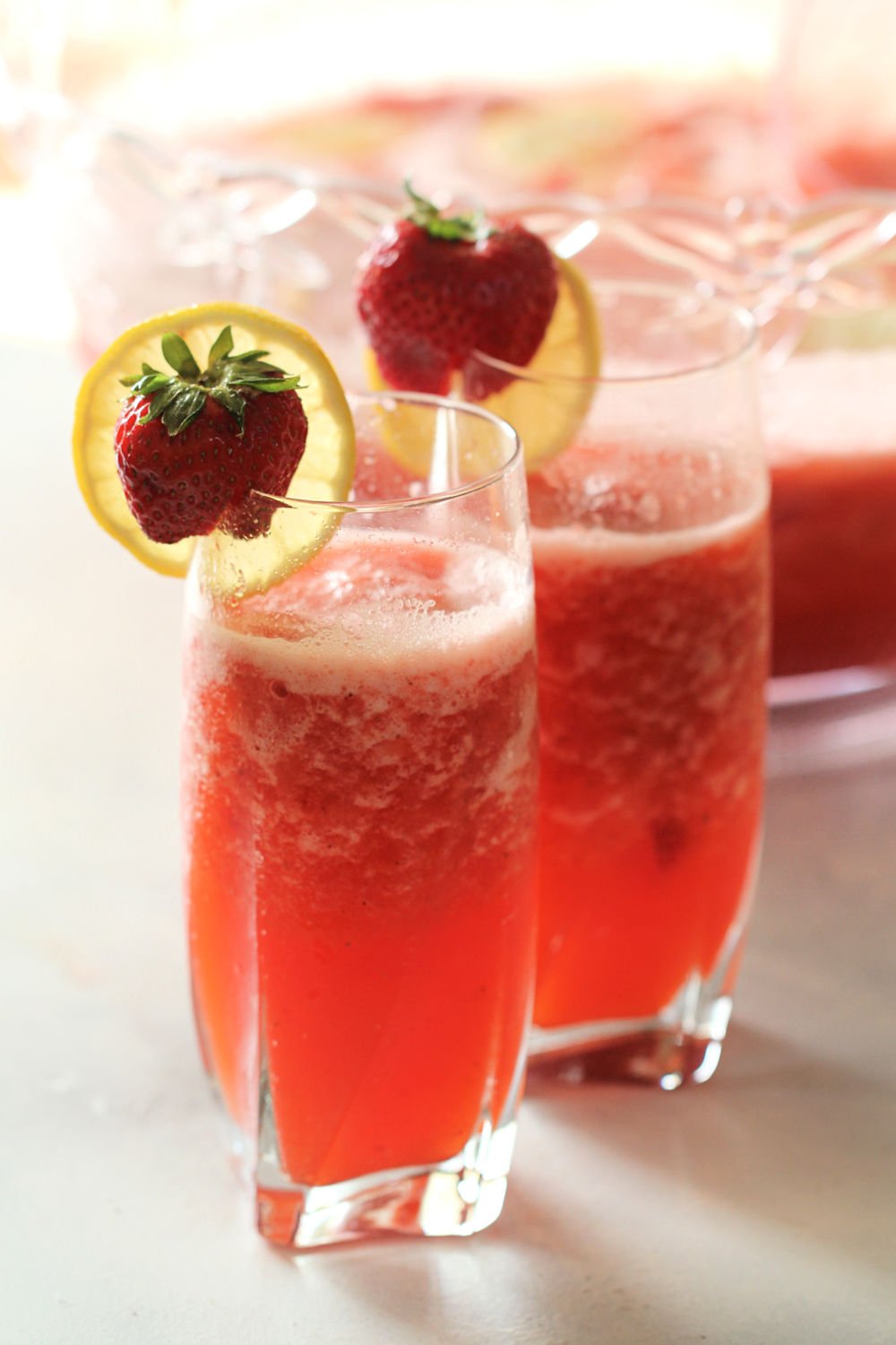 Strawberry Lemonade Slush Drink in glasses with strawberry and lemon garnishes