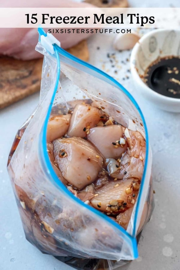 A plastic bag filled with marinated chicken pieces, placed on a countertop. A bowl with dark liquid and spices is in the background.