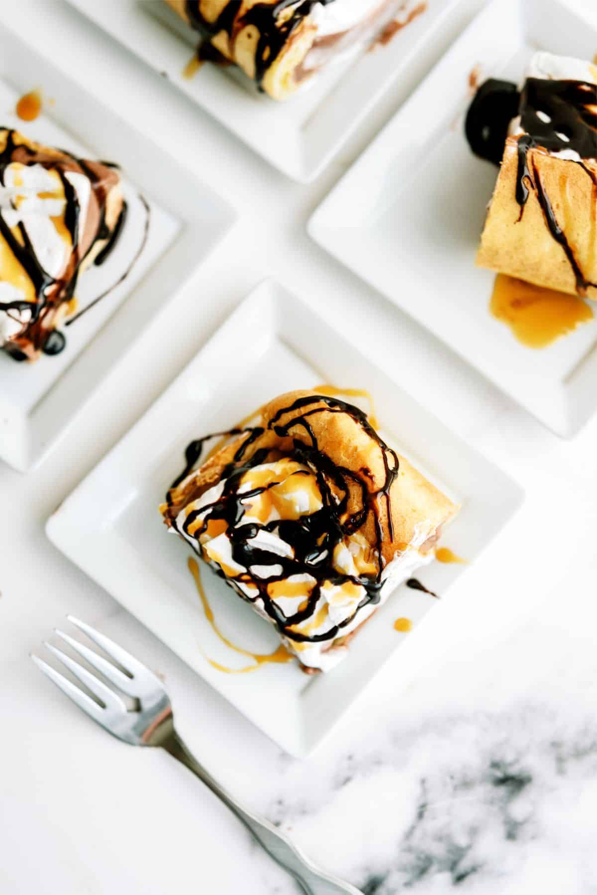 Top view of several plates with Cream Puff Cake Dessert slices on them and topped with chocolate drizzle.