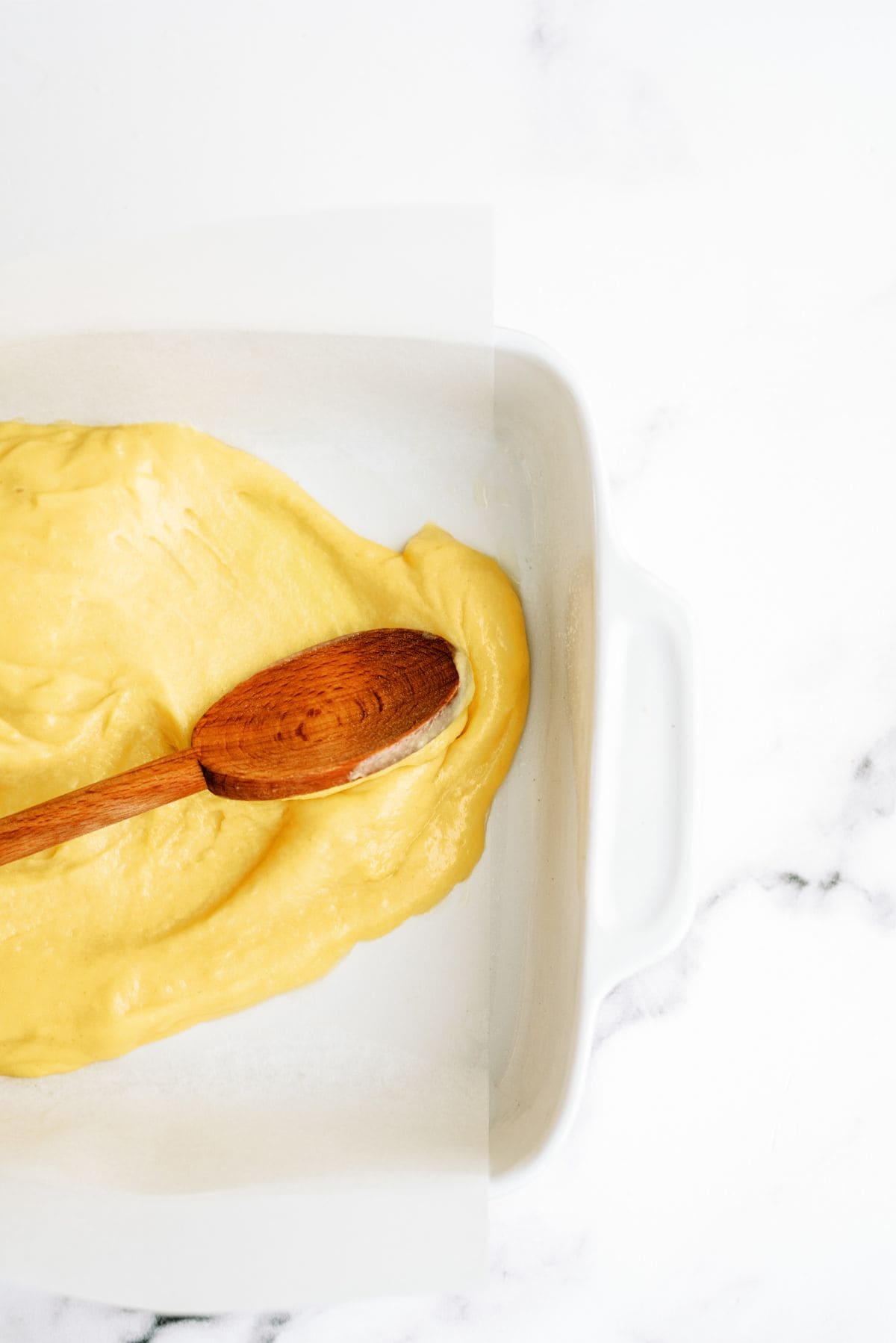 Spoon spreading cream puff dough in pan