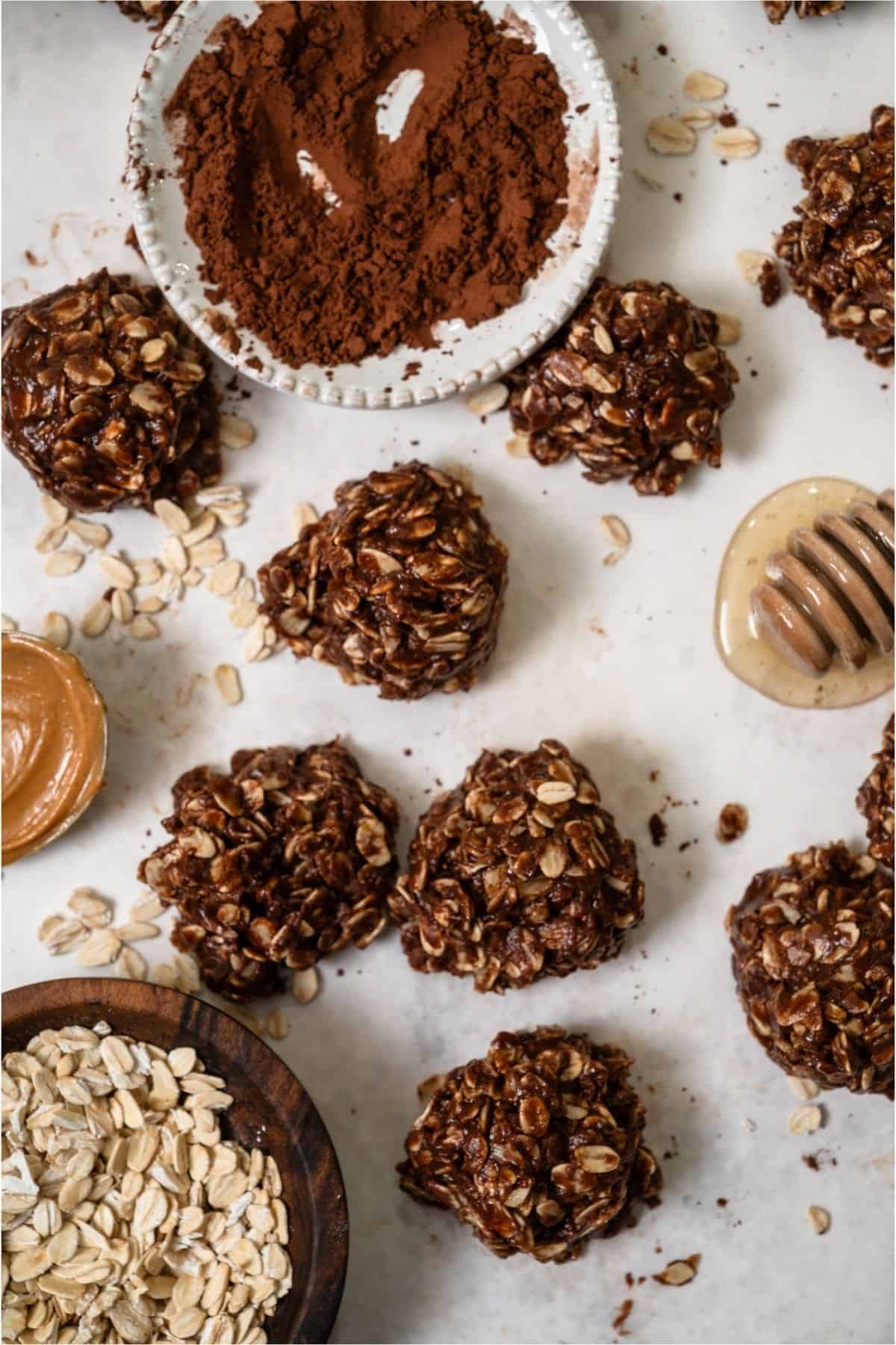 Healthier No Bake Chocolate Peanut Butter Cookies with a bowl of cocoa powder, a spoon of peanut butter and honey.