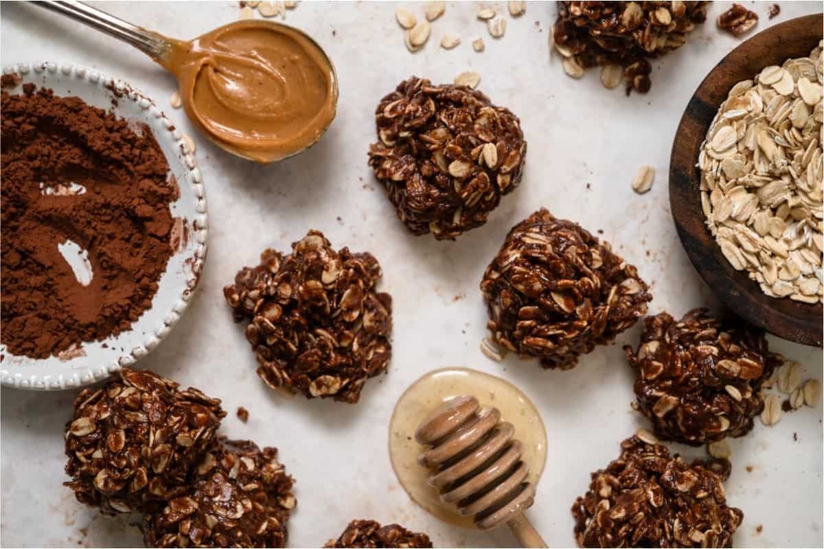 Healthier No Bake Chocolate Peanut Butter Cookies with a bowl of cocoa powder a spoon of peanut butter and honey.