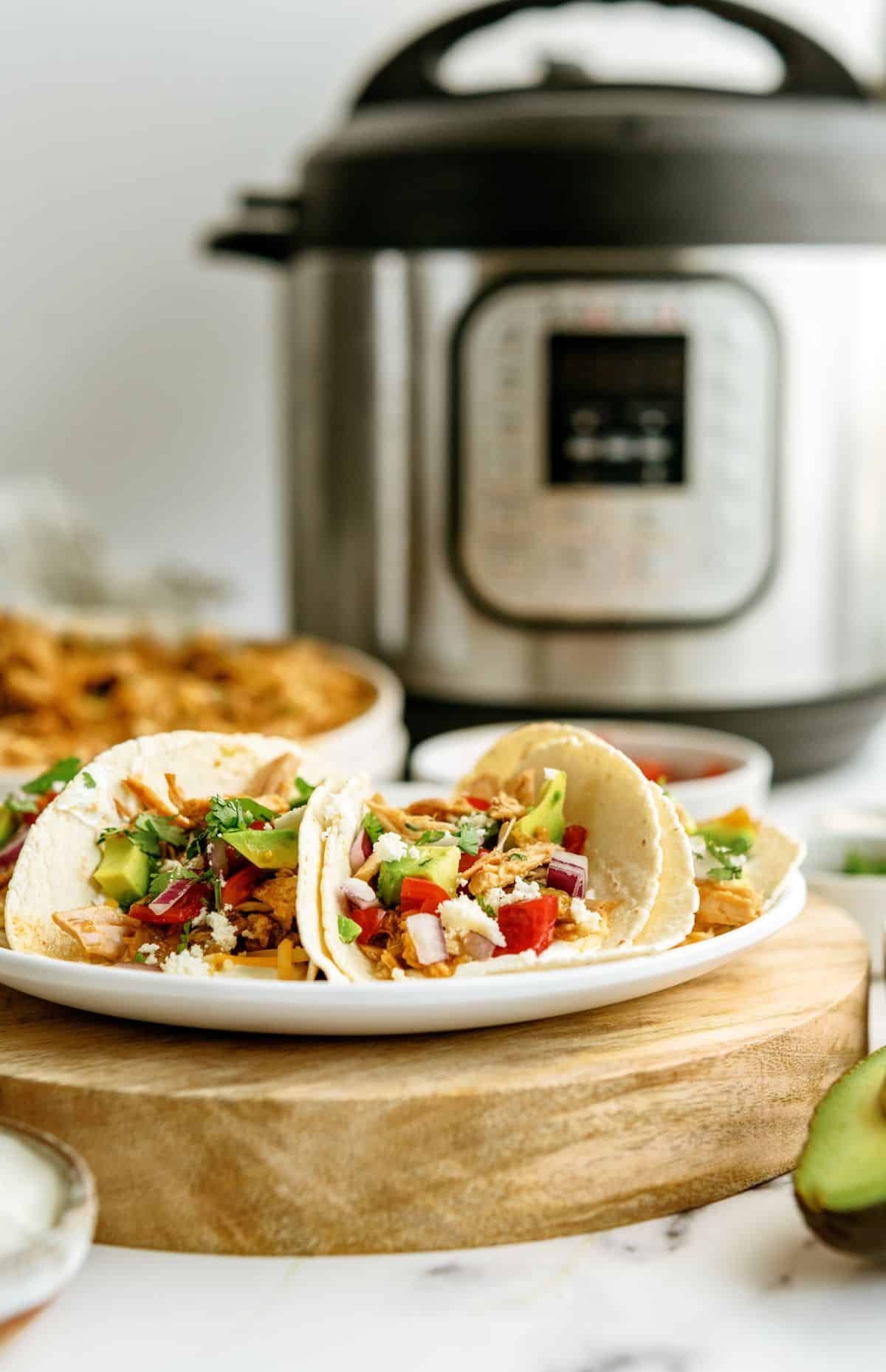 2 Instant Pot Green Chile Pork Tacos on a plate with the Instant Pot in the background