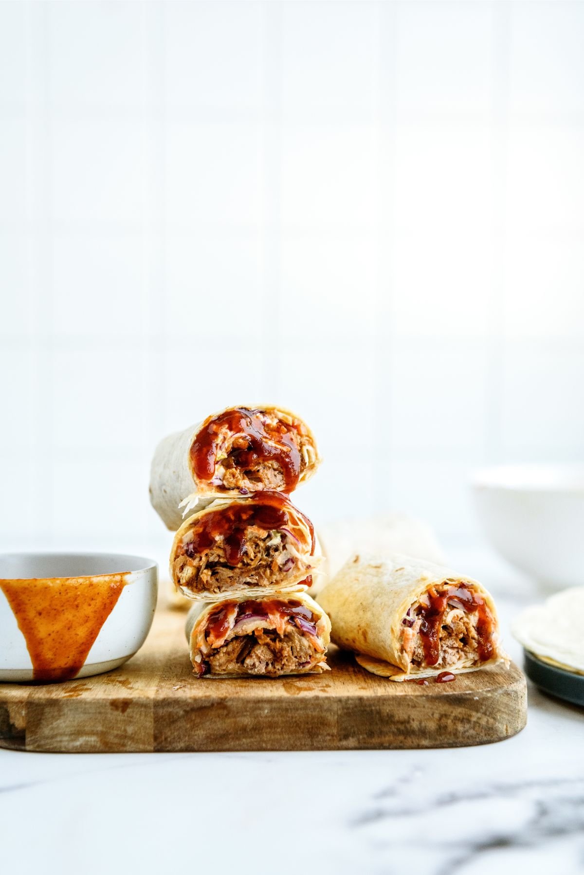 Instant Pot Honey BBQ Pork Wraps stacked on top of a cutting board