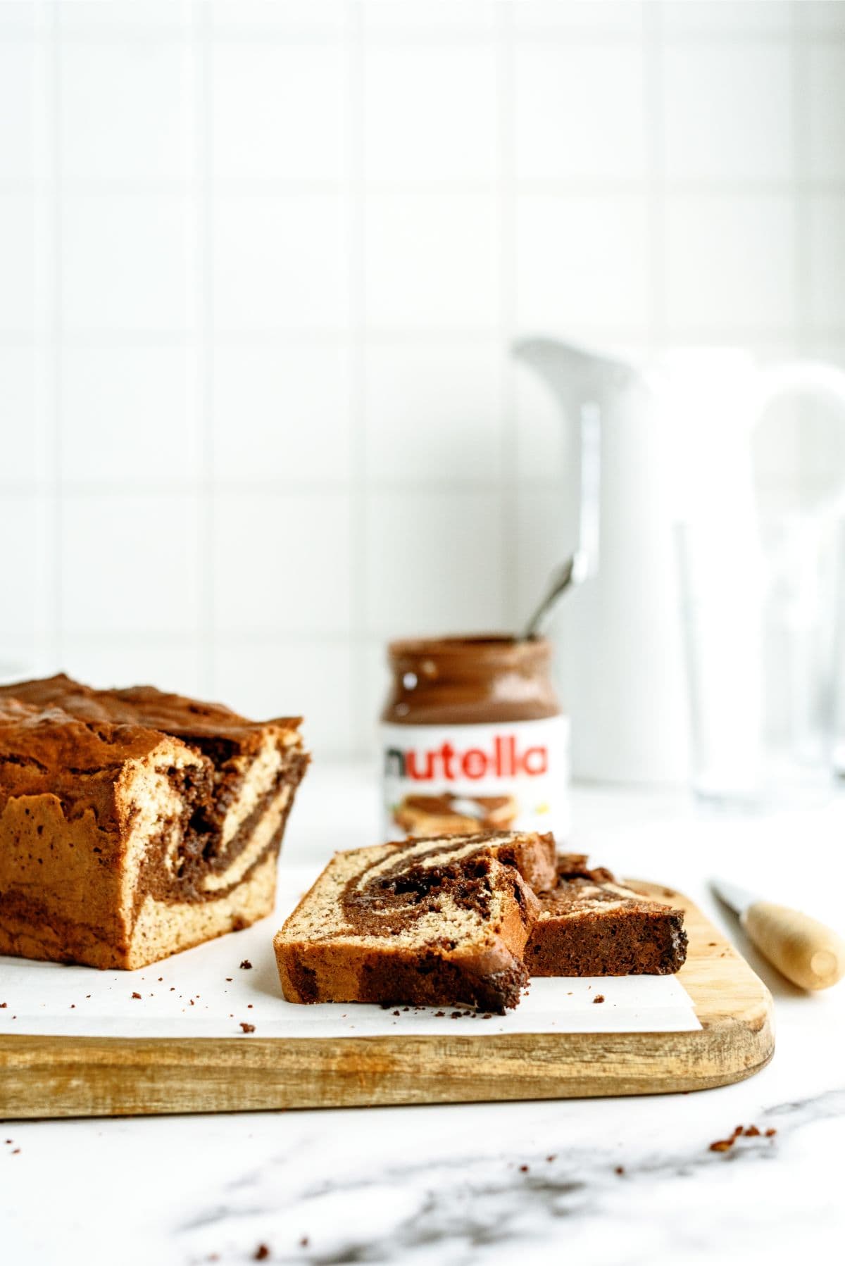 Nutella Banana Bread sliced on a cutting board with nutella in the background