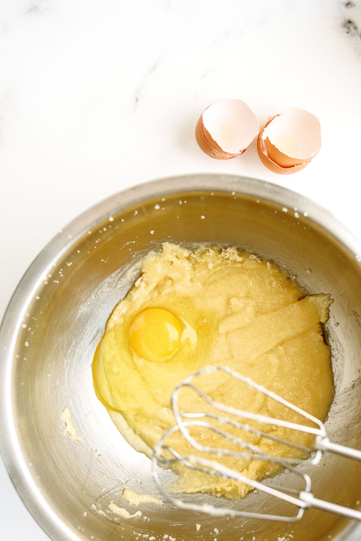 Adding eggs one at a time mixing into sugar mixture