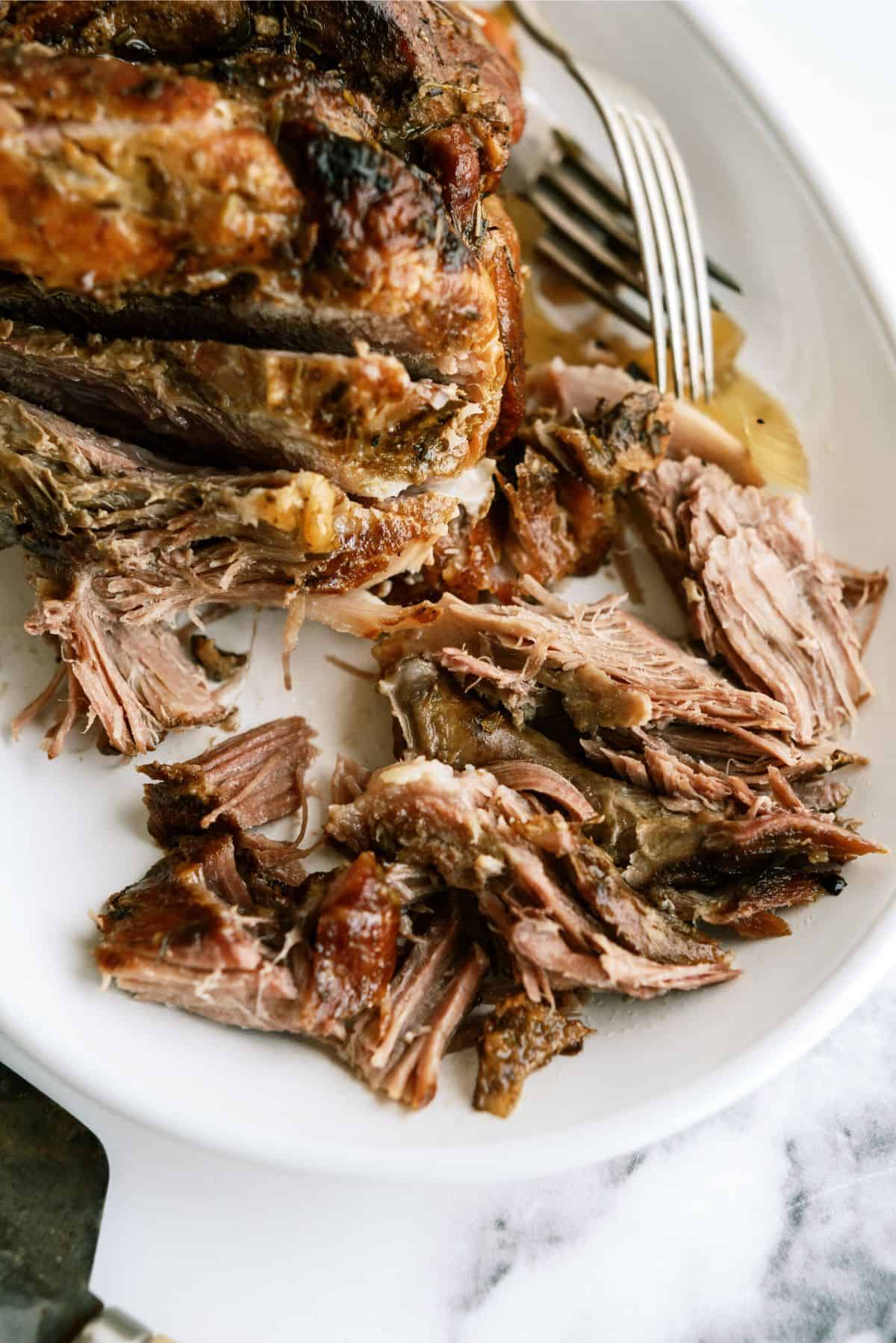 Oven Roasted Pork Shoulder shredded on a serving plate with 2 forks