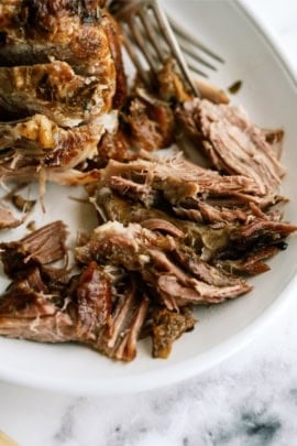 Shredded cooked pork meat served on a white plate.