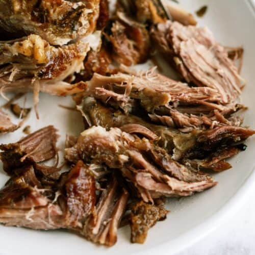 Shredded cooked pork meat served on a white plate.
