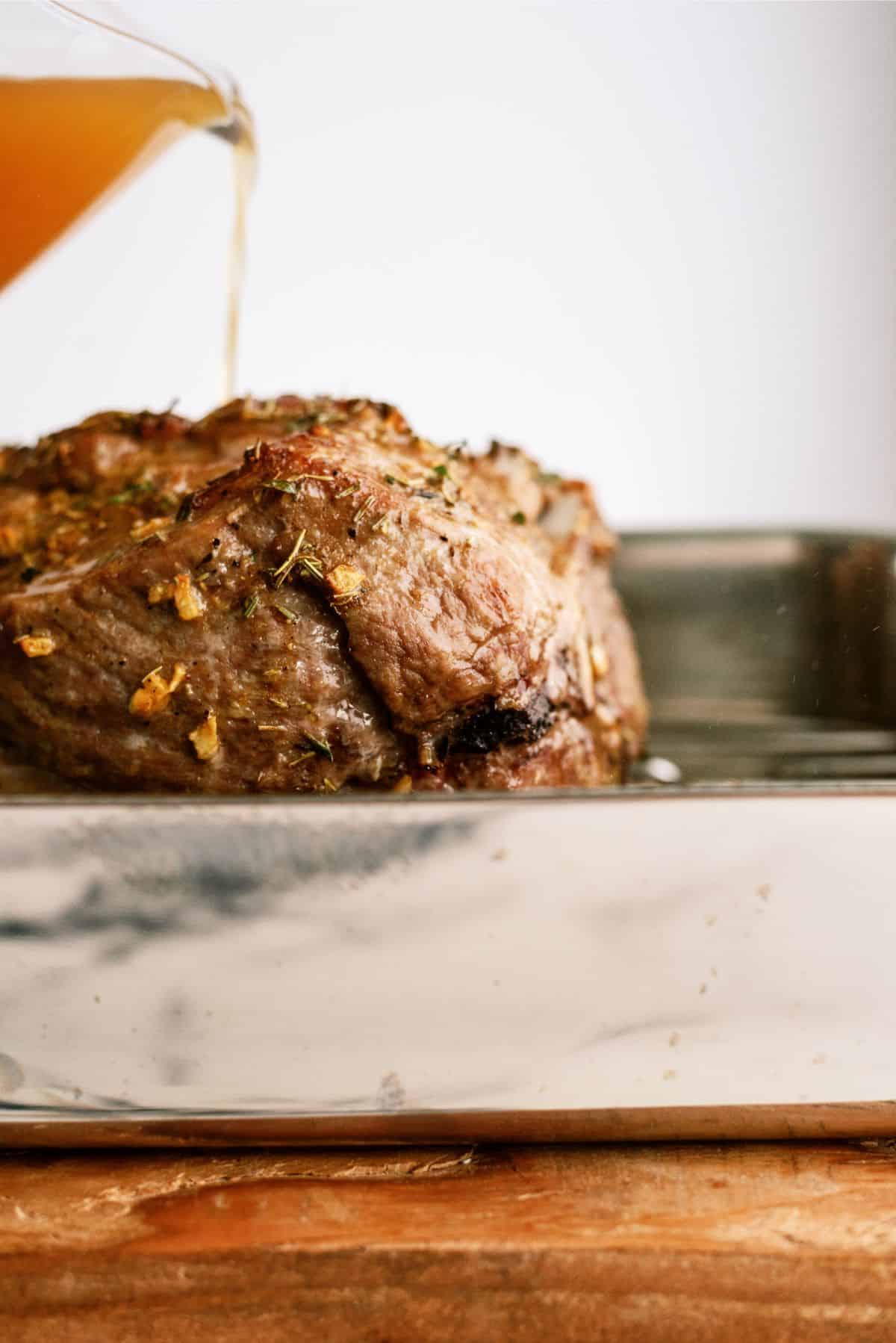 Pouring broth mixture on roast in pan